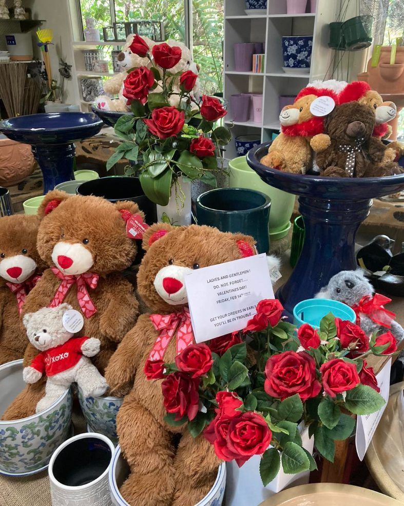 A Bunch of Teddy Bears Are Sitting on a Table With Red Roses — Wingham Nursery and Florist PTY Ltd In Wingham, NSW