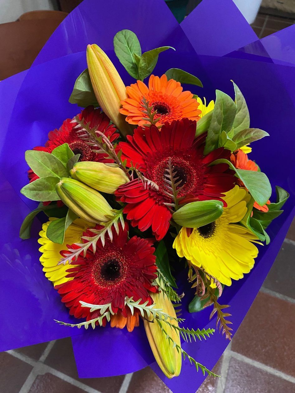 A Bouquet of Flowers Wrapped in Purple Paper — Wingham Nursery and Florist PTY Ltd In Wingham, NSW