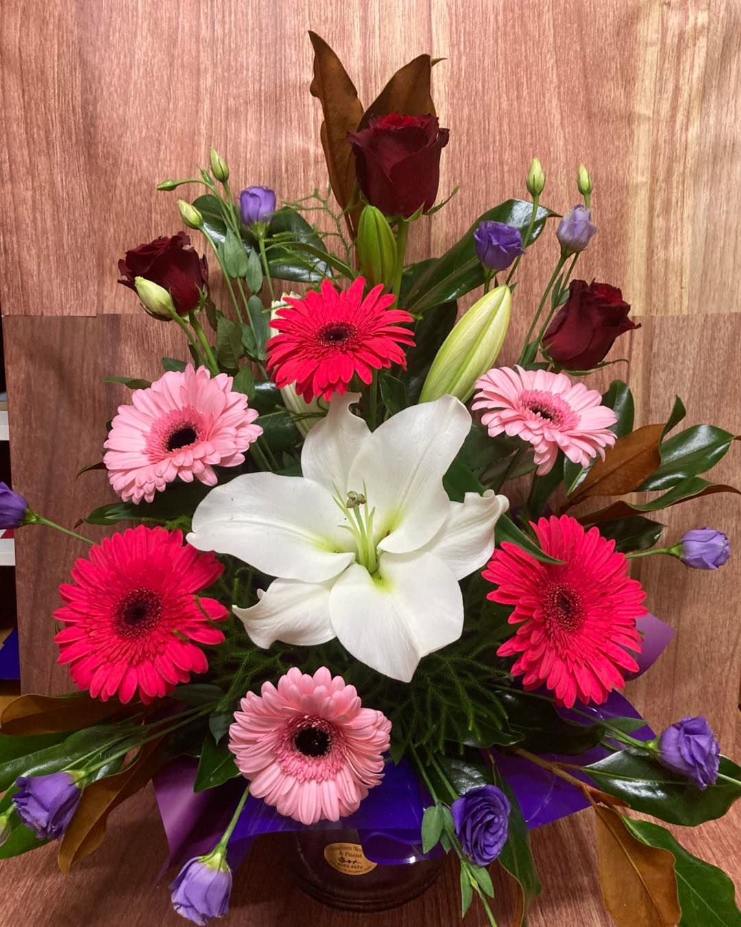 A Vase Filled With Flowers is Sitting on a Wooden Table — Wingham Nursery and Florist PTY Ltd In Wingham, NSW