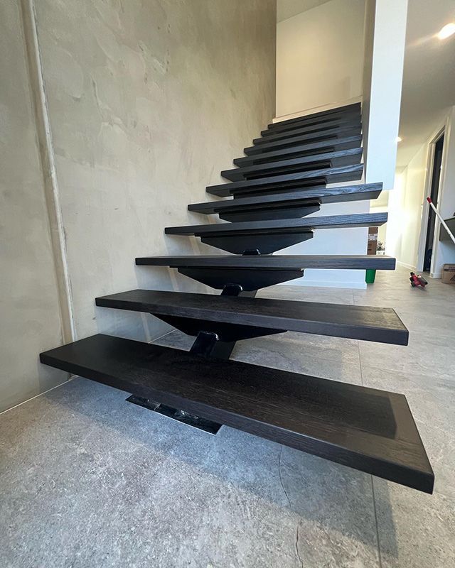 A Black Staircase With Wooden Steps In A House — Hardwood Projects in Canberra, ACT