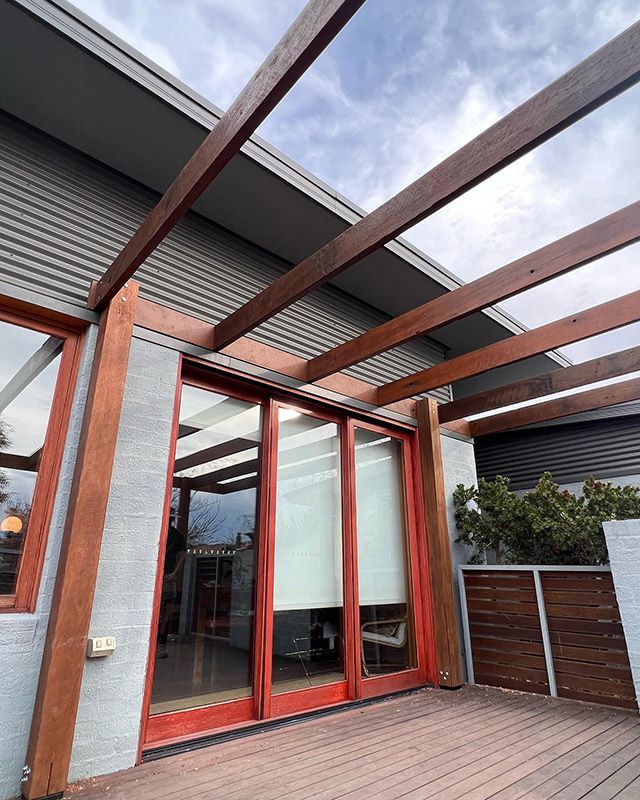 A House With Red Sliding Glass Doors And A Wooden Deck — Hardwood Projects in Canberra, ACT