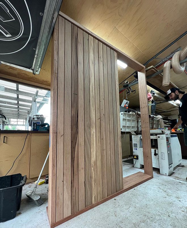 A Man Working On A Wooden Wall In A Workshop — Hardwood Projects in Canberra, ACT