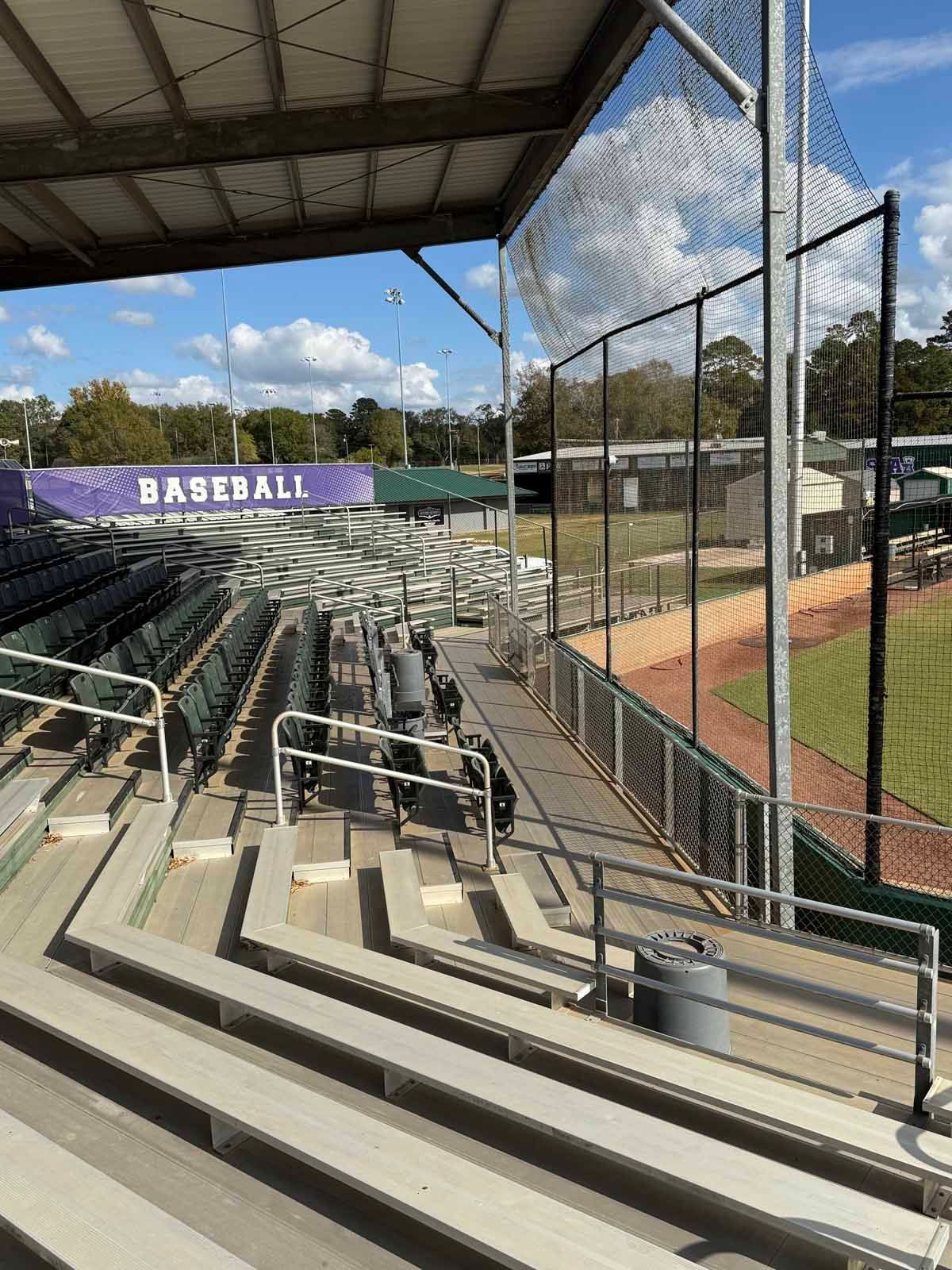 Baseball stadium seating with protective netting along the edge, overlooking the field. Empty stands.