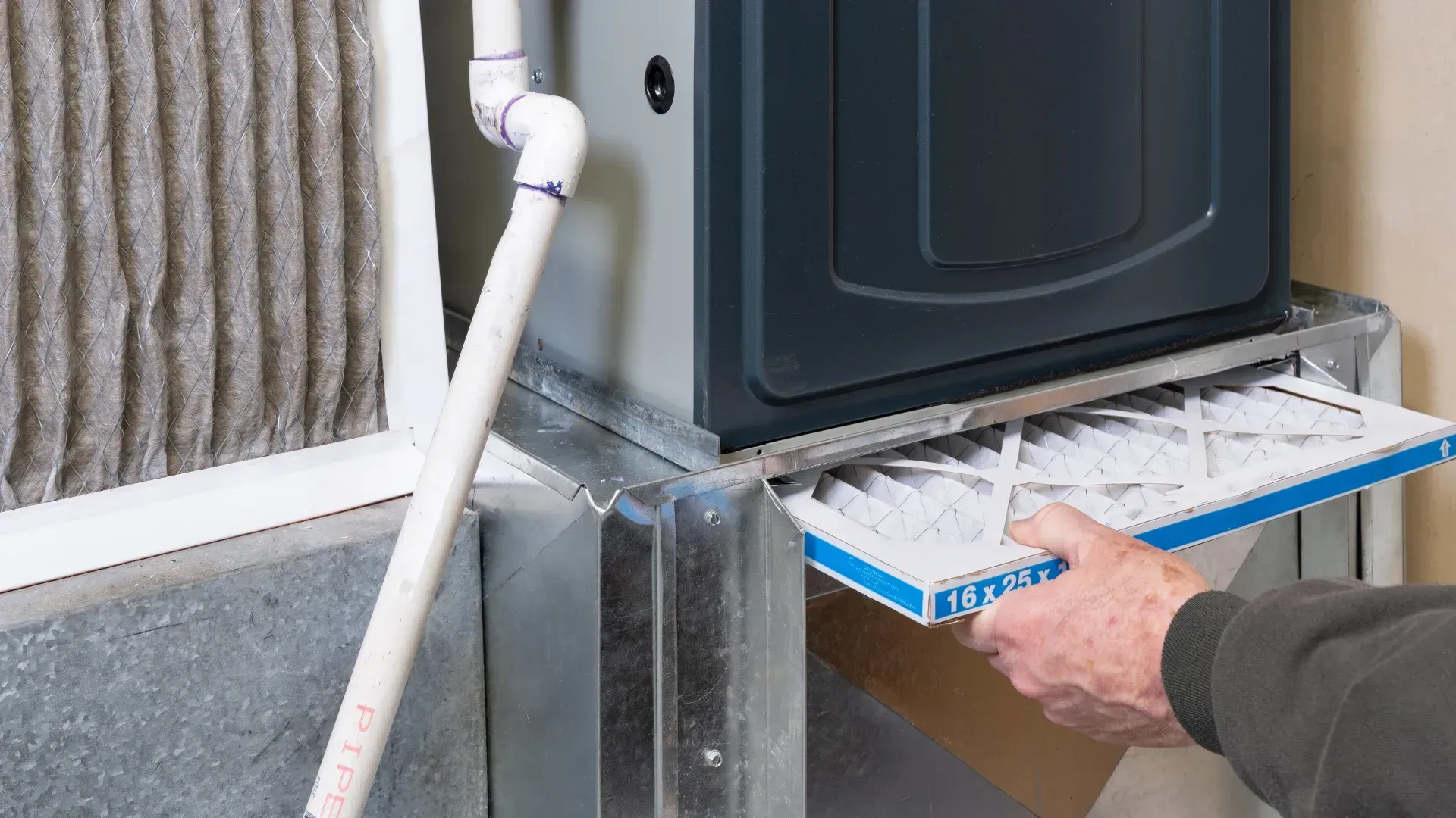A person is cleaning a furnace with a vacuum cleaner.