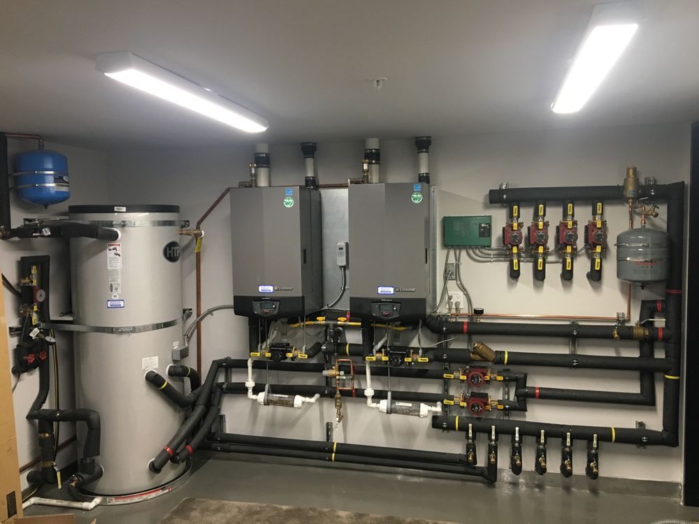 A room with a lot of pipes and heaters on the wall.