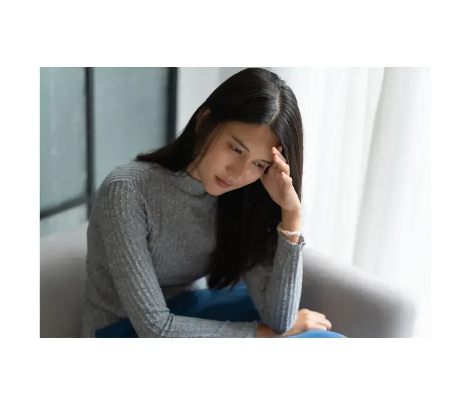 Woman sitting thoughtfully, appearing anxious or stressed.