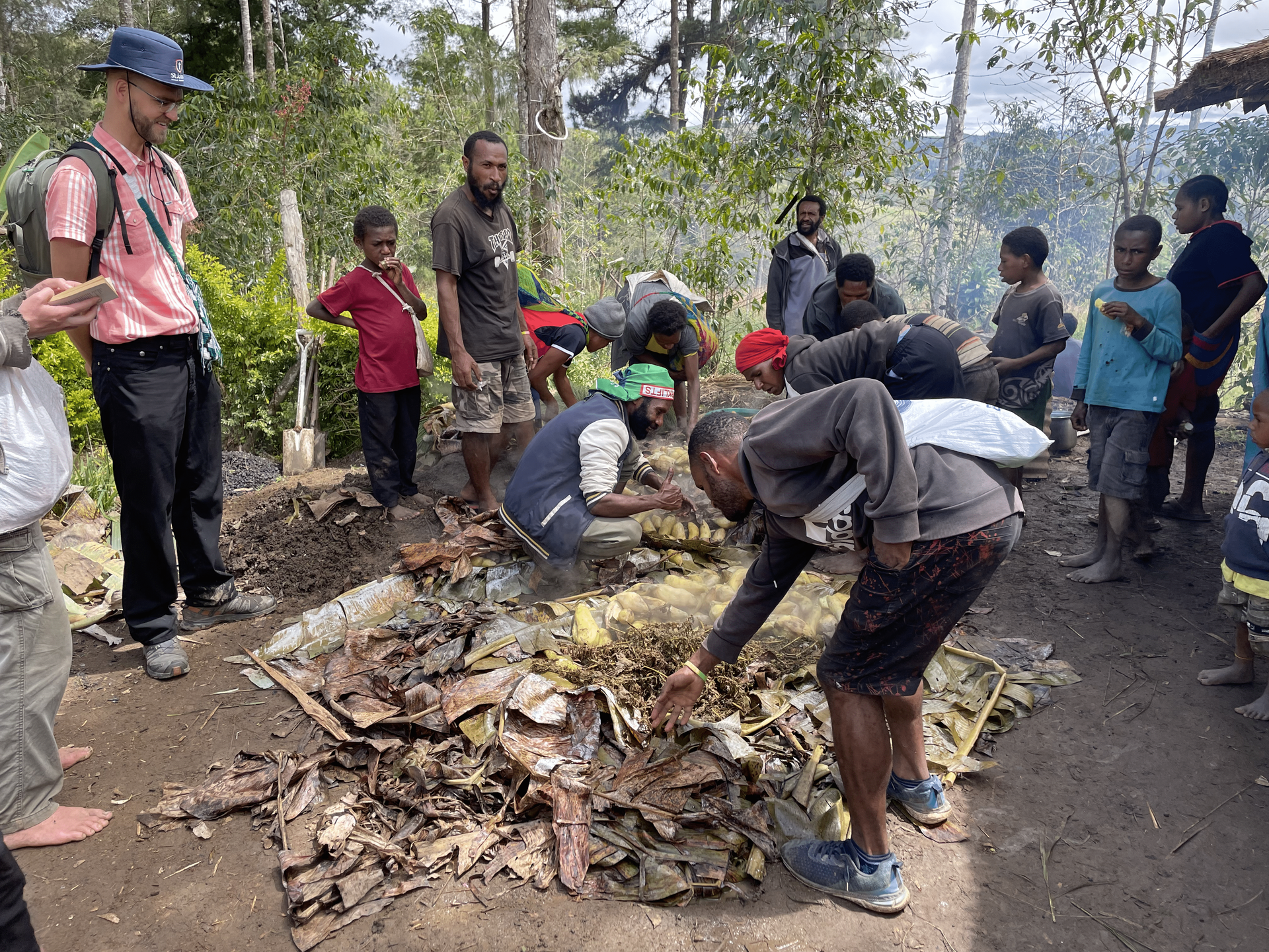 Een groep mensen staat rond een stapel hout. Papoea-Nieuw-Guinea 