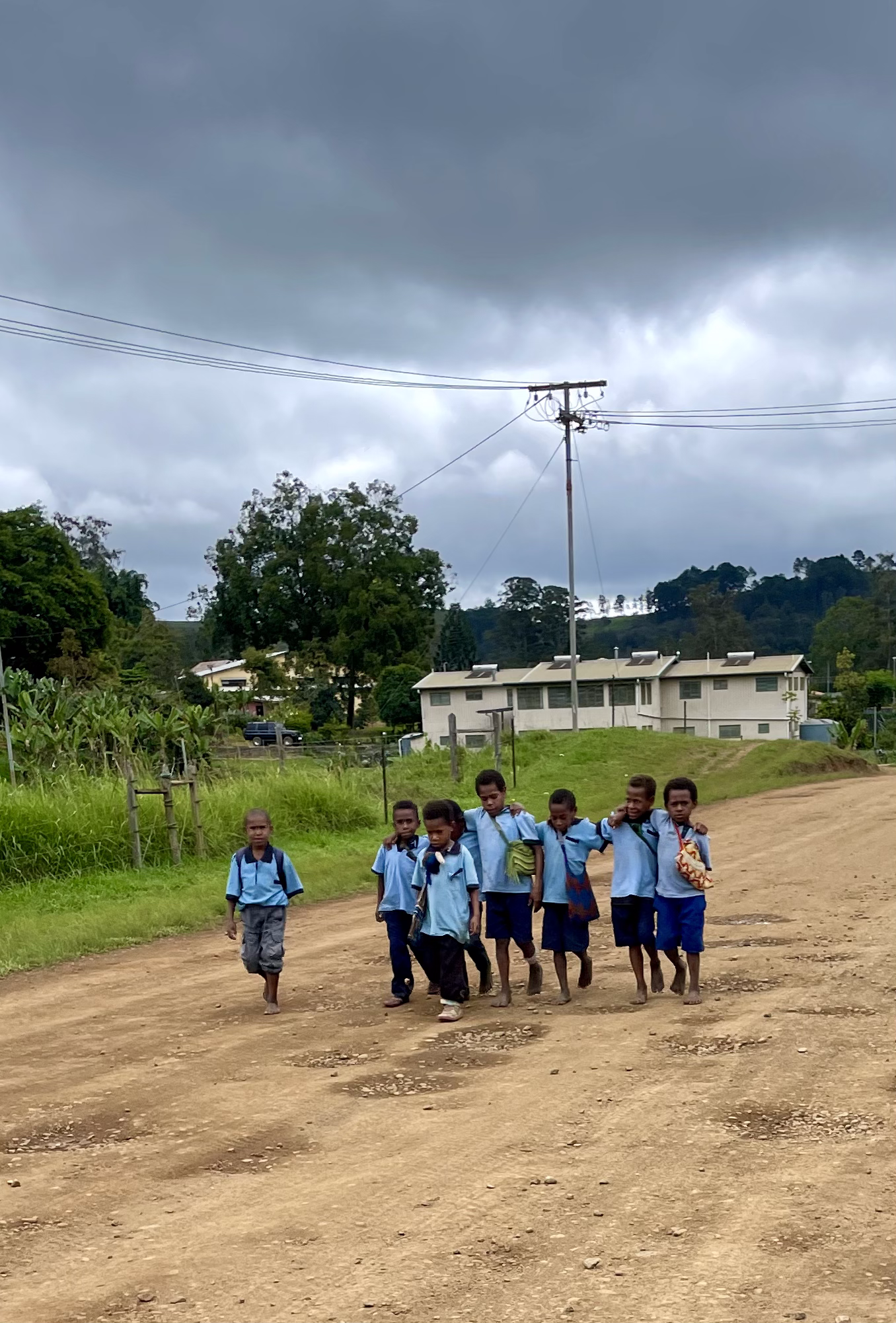 Een groep kinderen loopt over een onverharde weg. Papoea-Nieuw-Guinea 