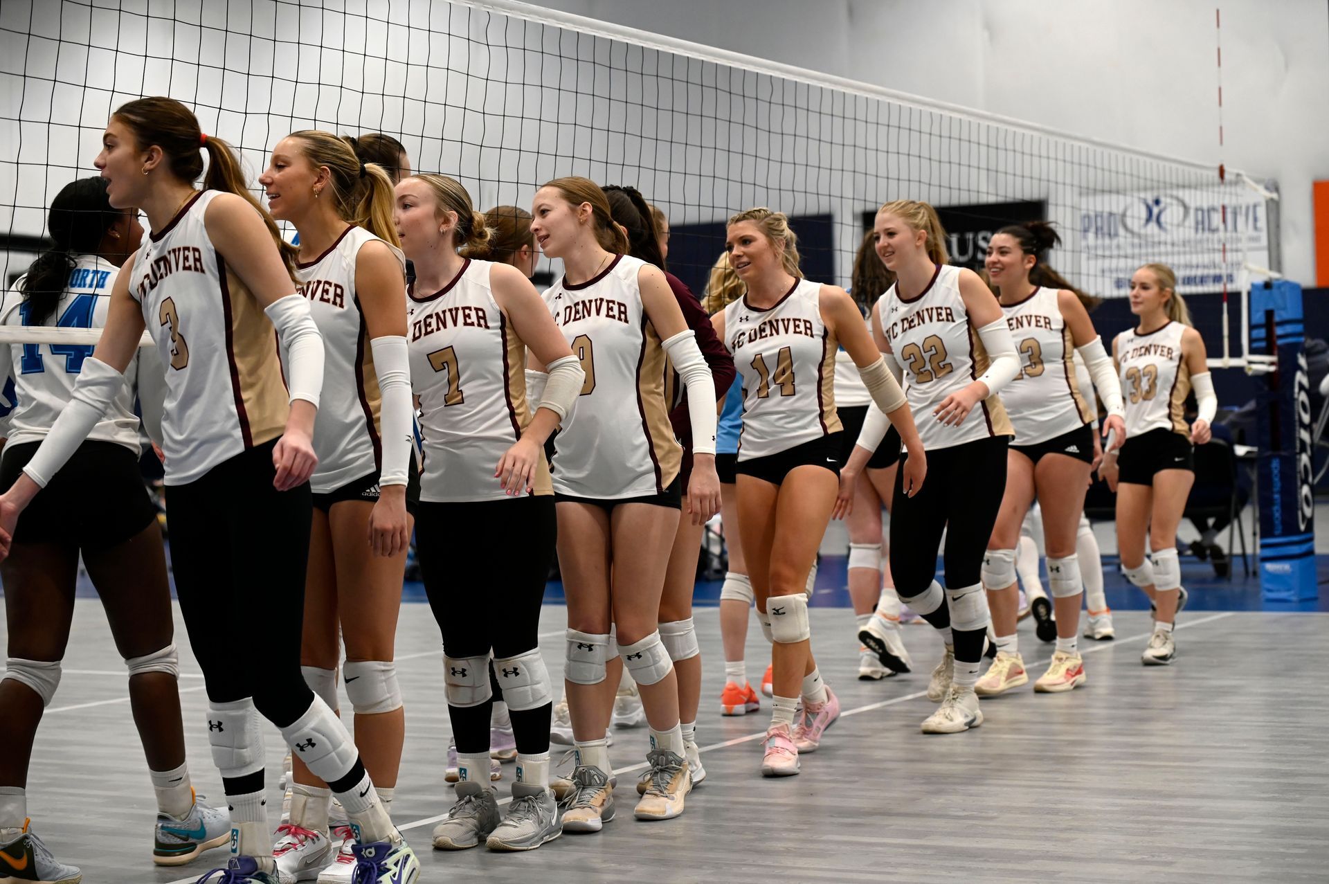 Volleyball team in white uniforms lined up on an indoor court, preparing to enter the game