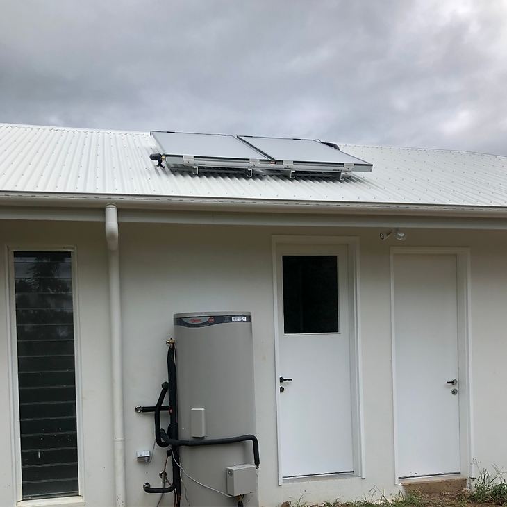 White house exterior with rooftop solar panels and a mounted utility unit by the door — Dunnerite Plumbing in Edmonton, QLD