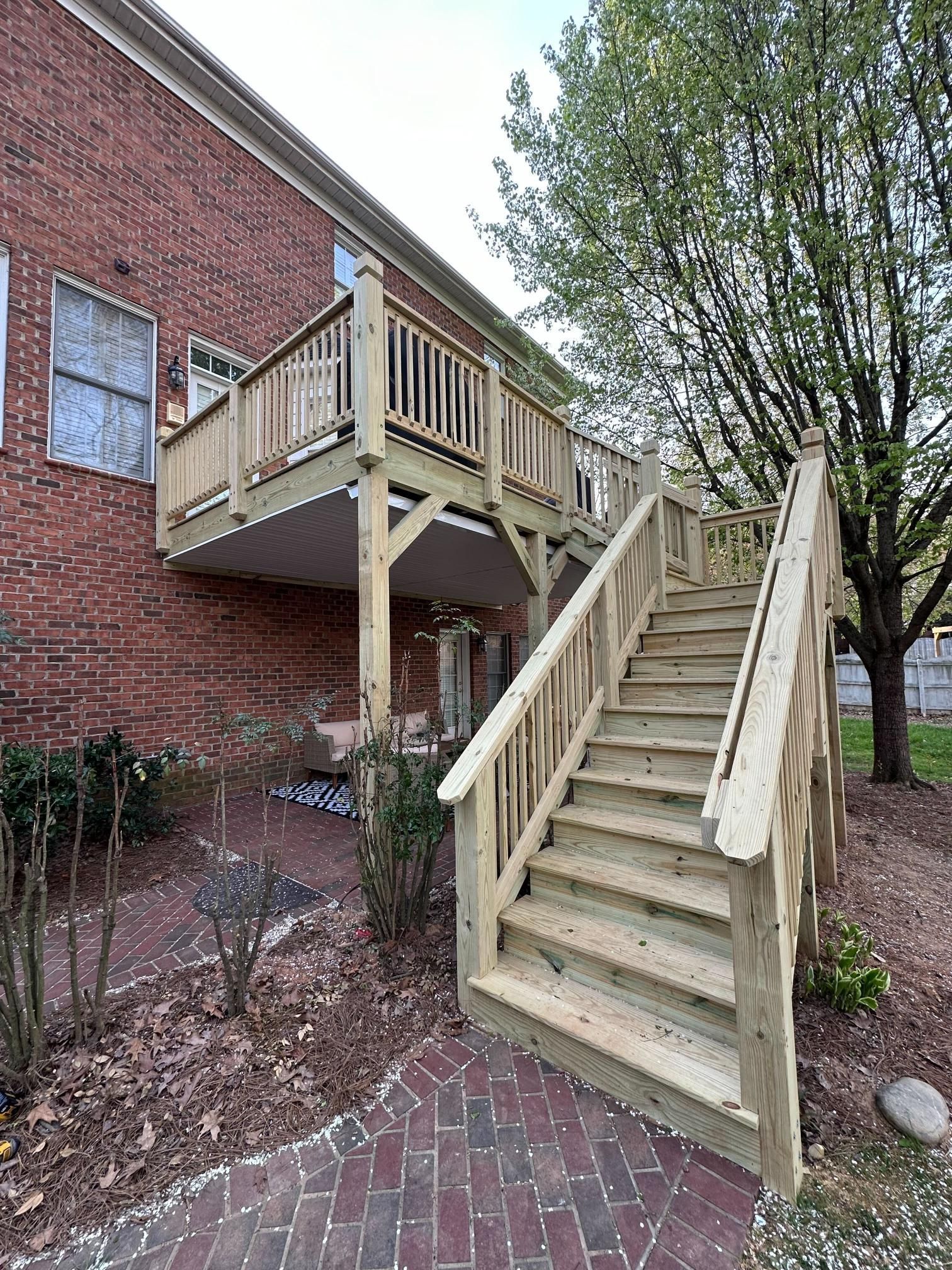 Wooden deck and stairs attached to a brick house.