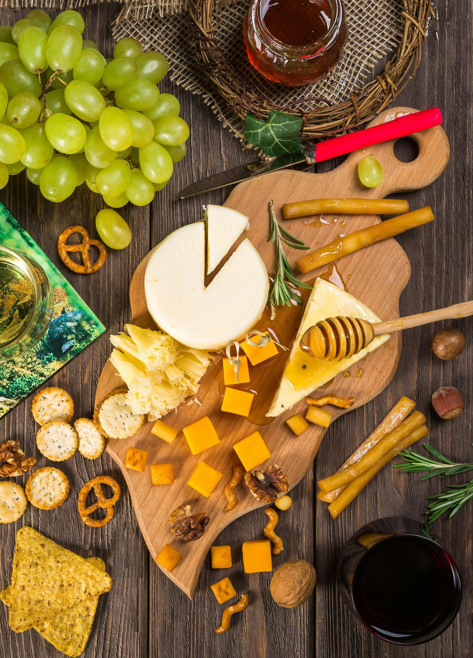 Cheese board with grapes, crackers, nuts, and wine. Wooden surface.