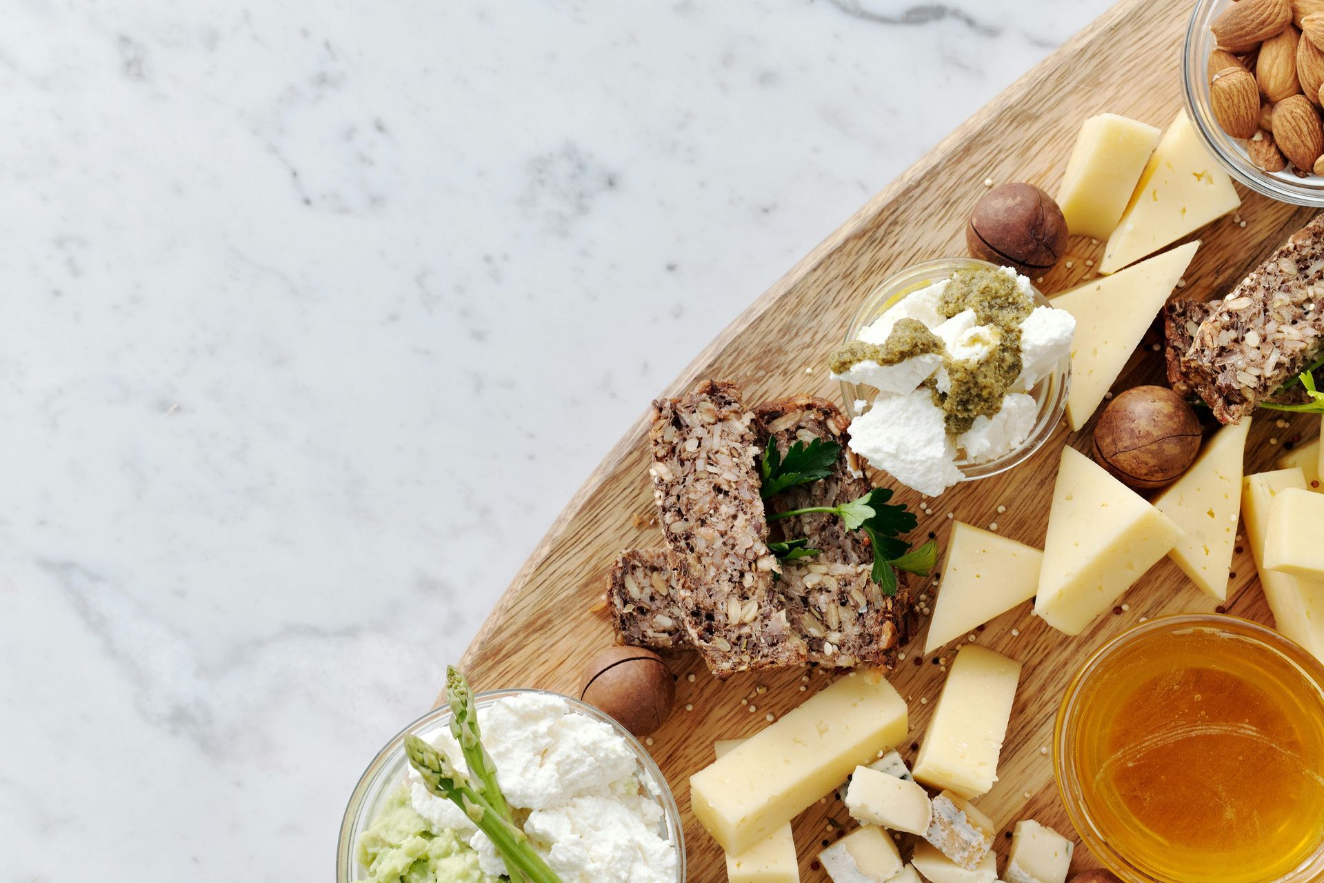 Cheese and nut board on a wooden surface with a marble background.