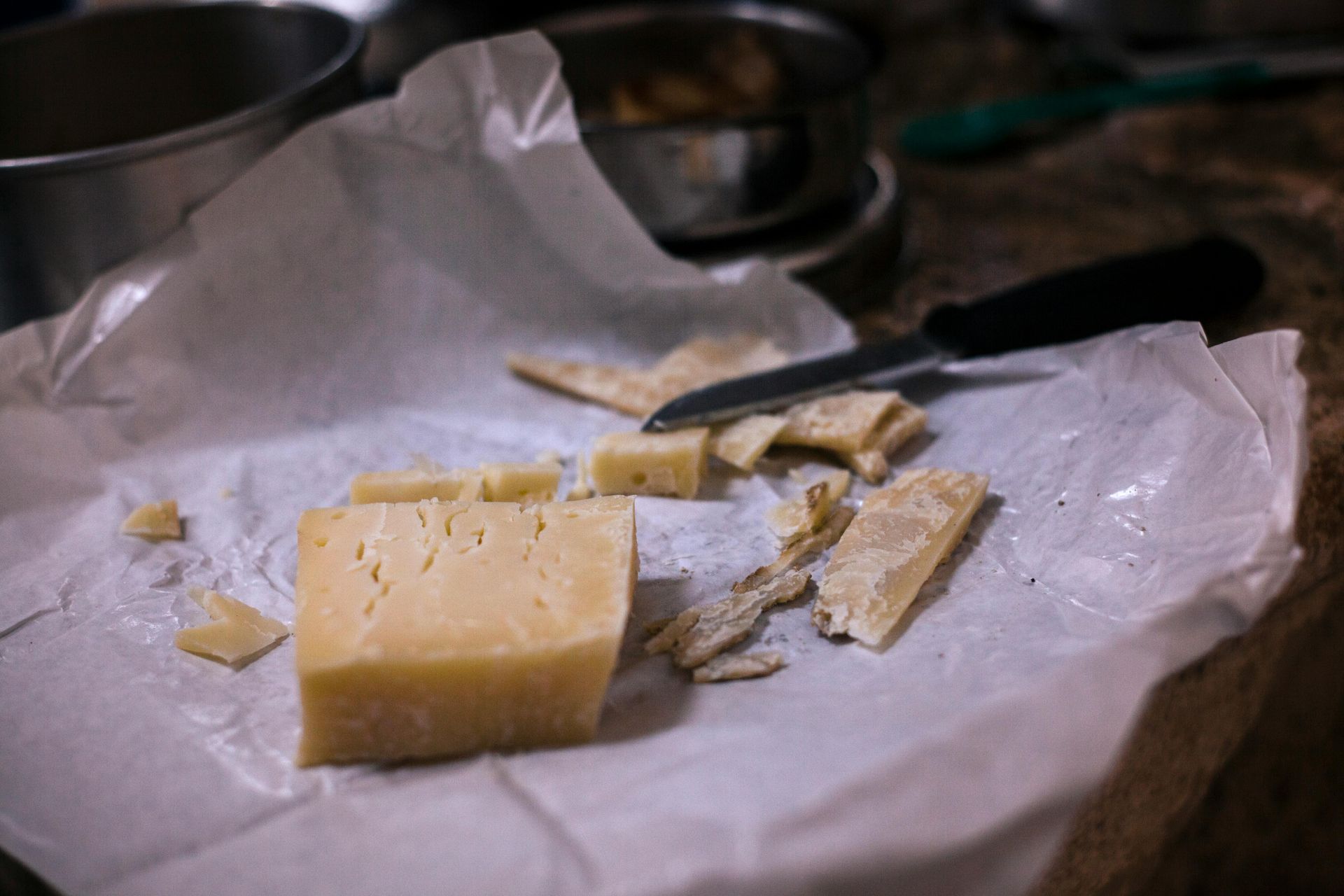 Cheese and crackers on parchment paper with a knife on a countertop.
