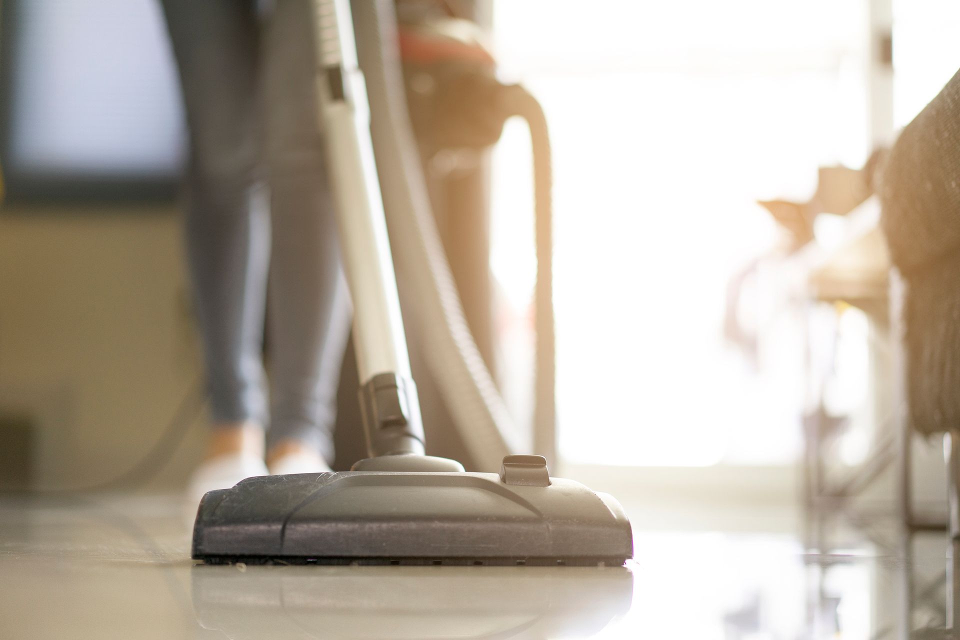 A person is using a vacuum cleaner to clean the floor.