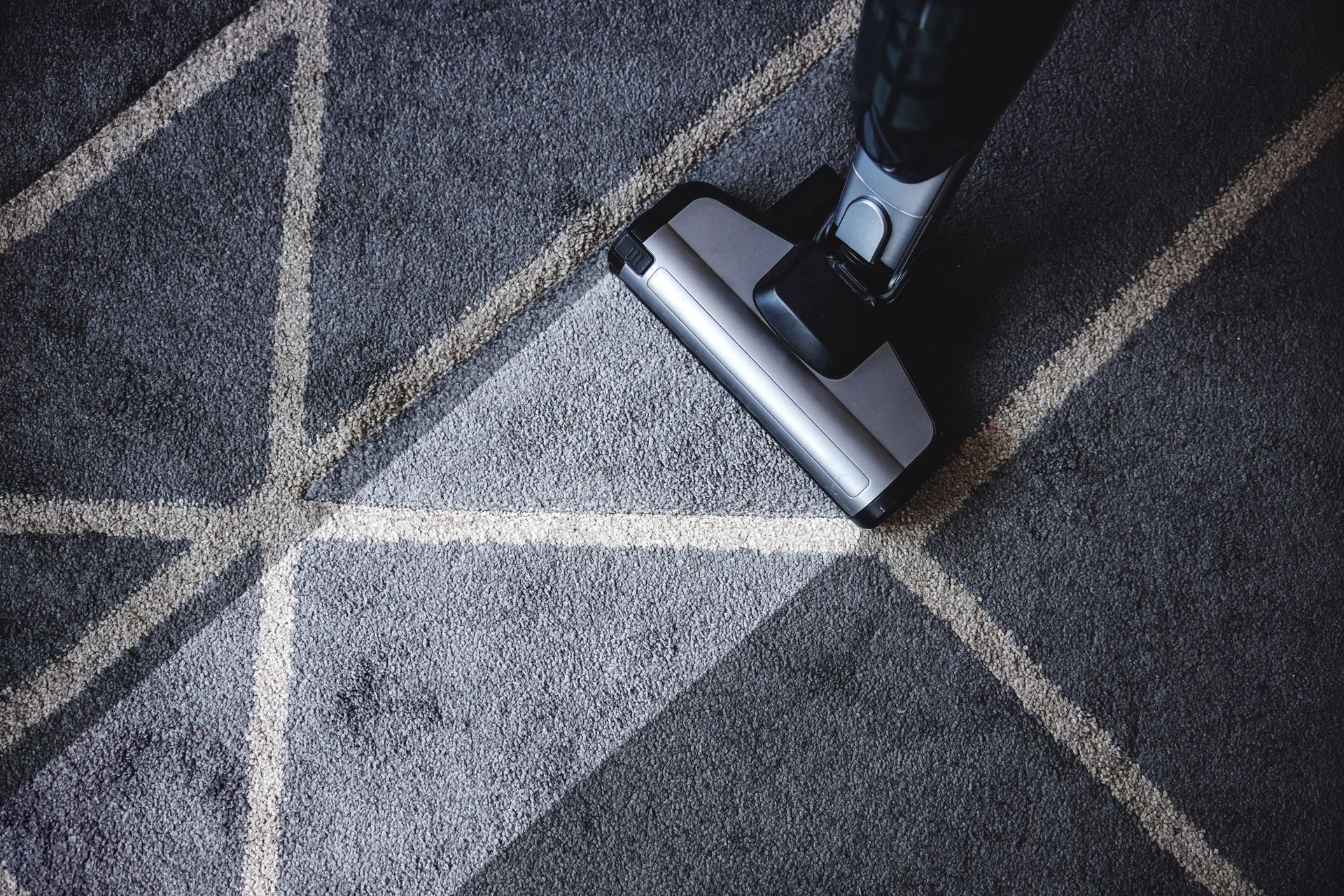 A person is using a vacuum cleaner to clean a carpet.