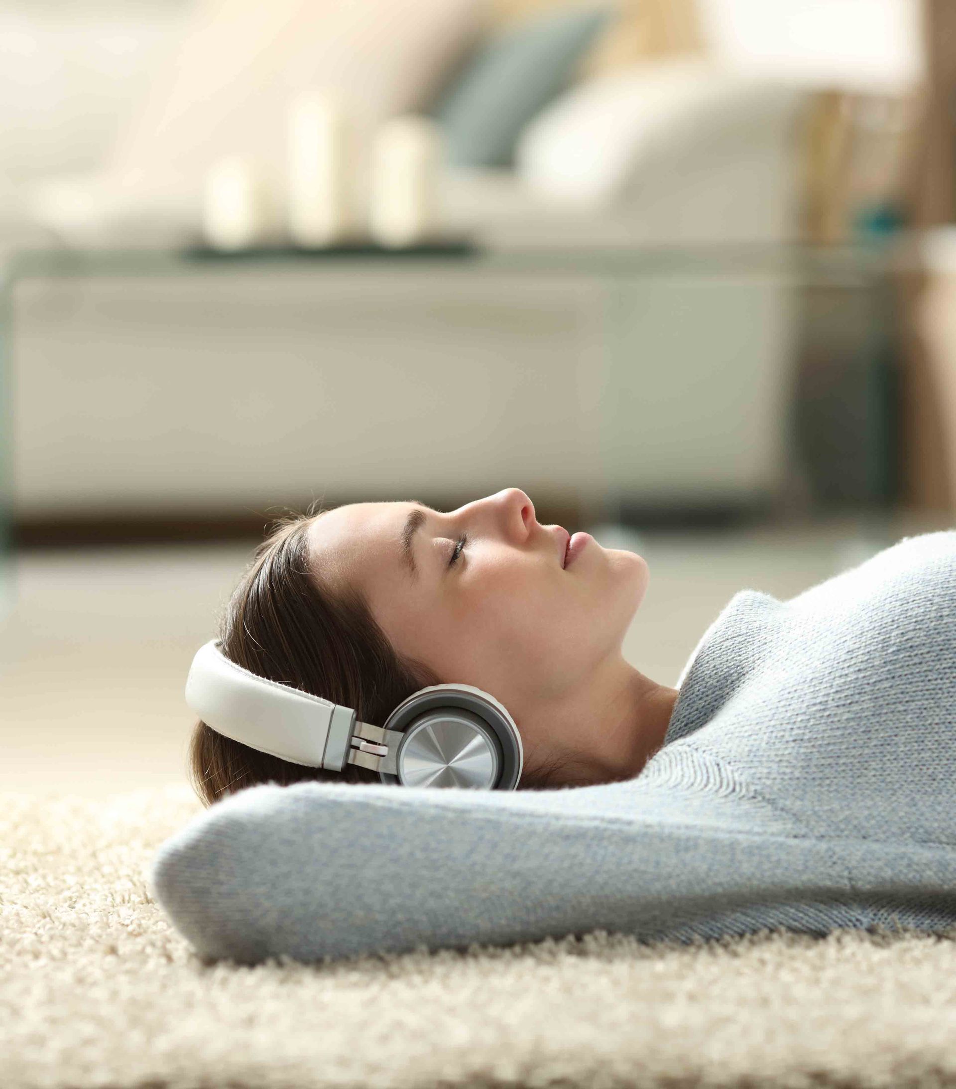 A woman is laying on the floor wearing headphones.