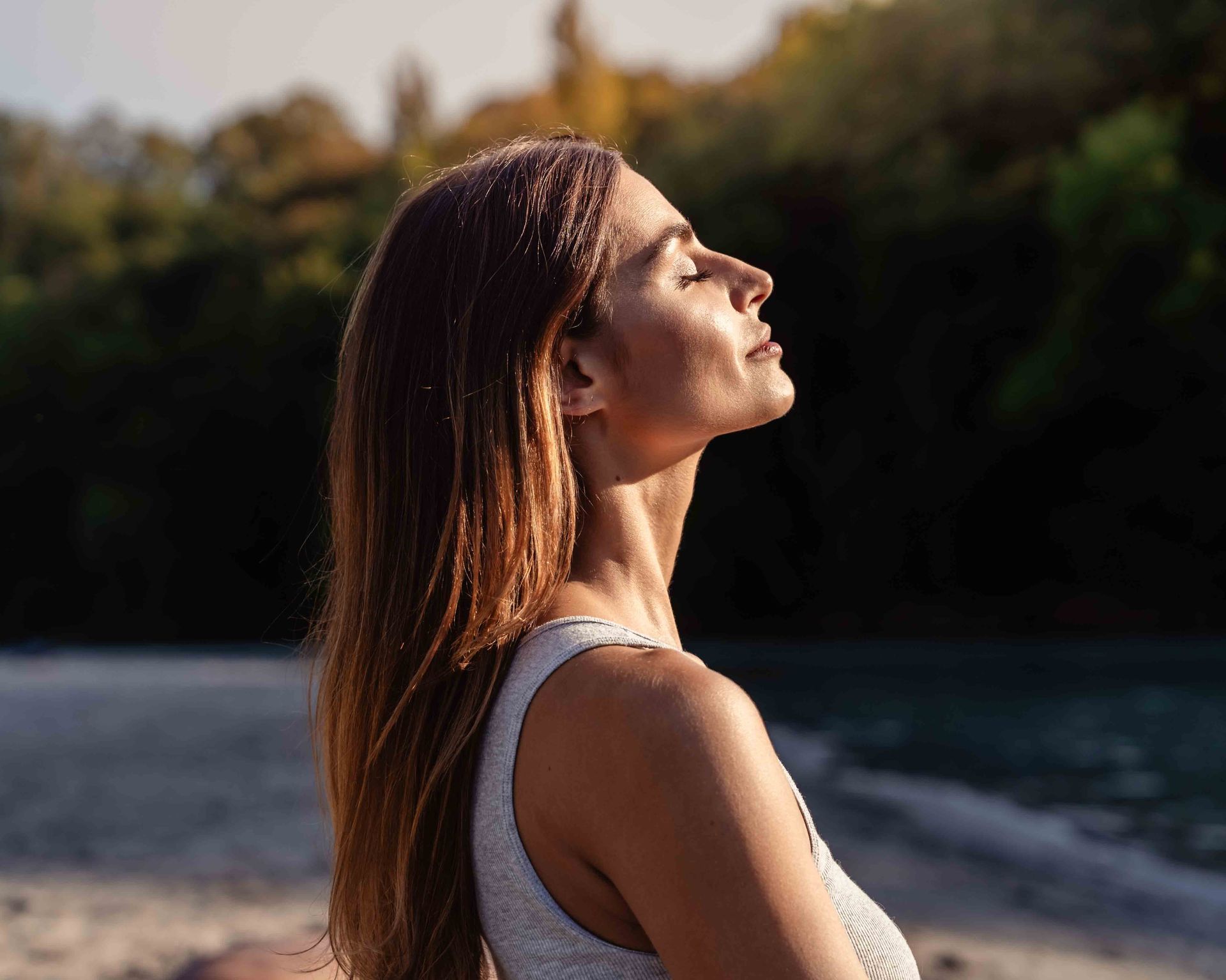 A woman is standing on a beach looking up at the sky.