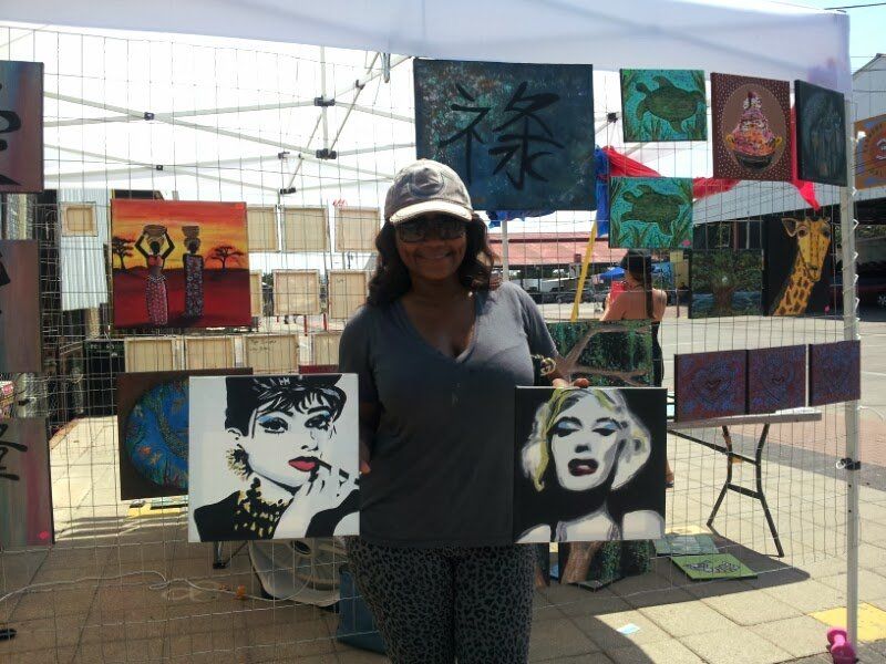 A woman is holding two paintings of audrey hepburn and marilyn monroe