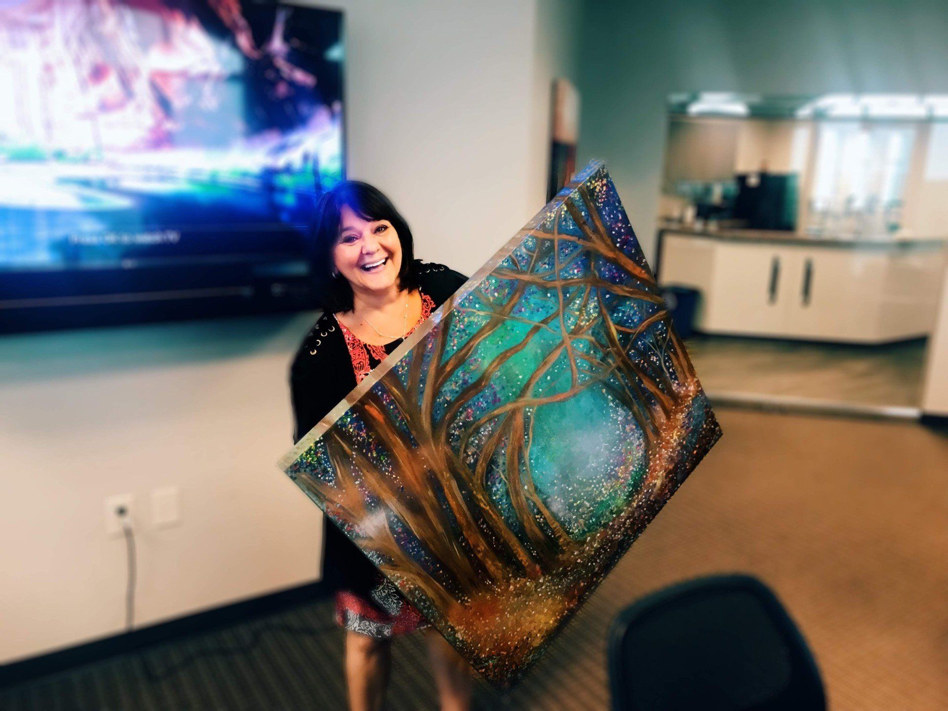 A woman is holding a large painting in her hands