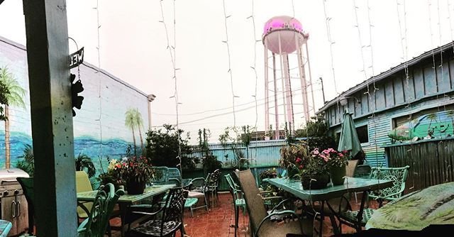 A patio with tables and chairs and a water tower in the background.