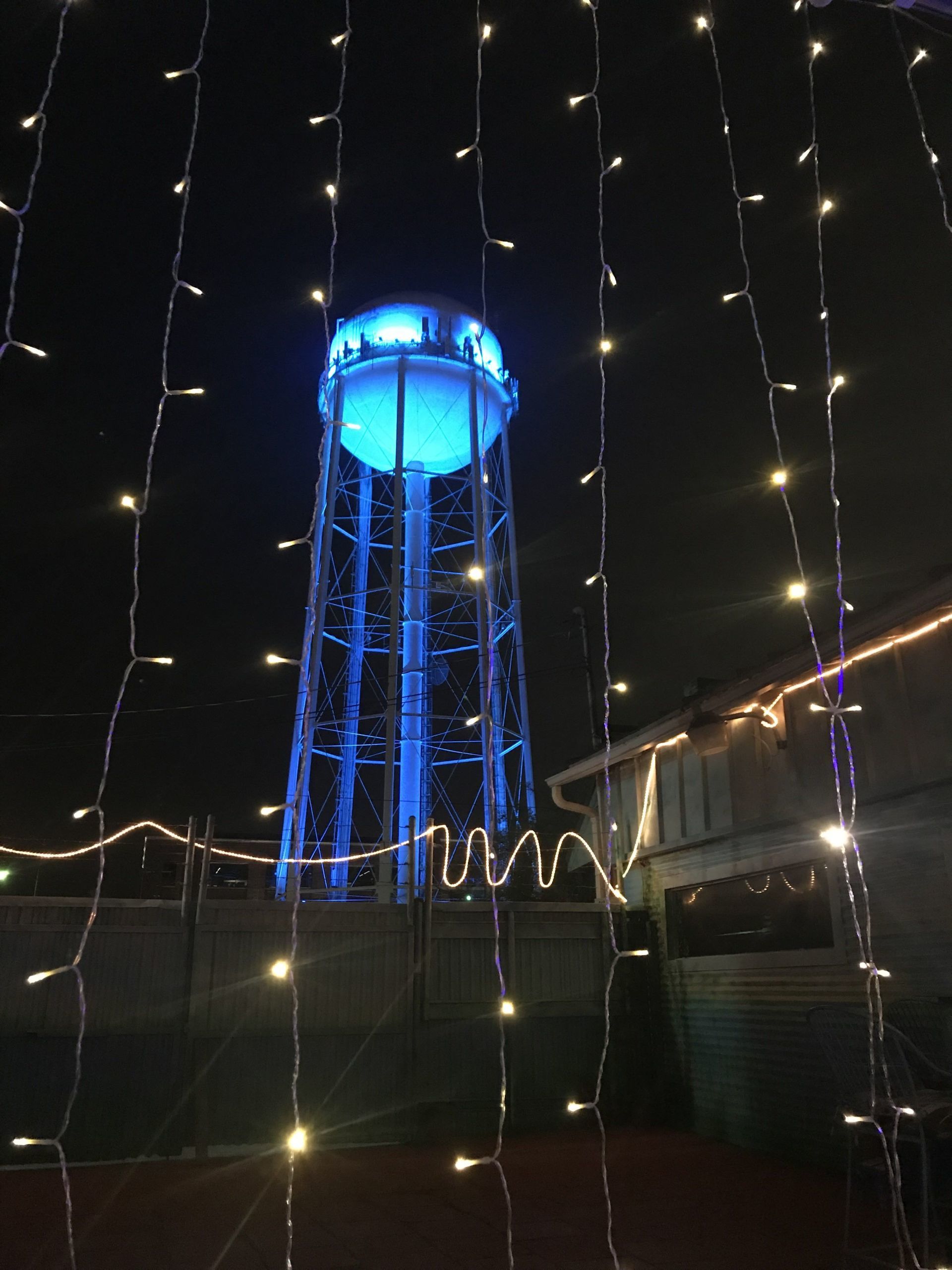A water tower is lit up with blue lights at night