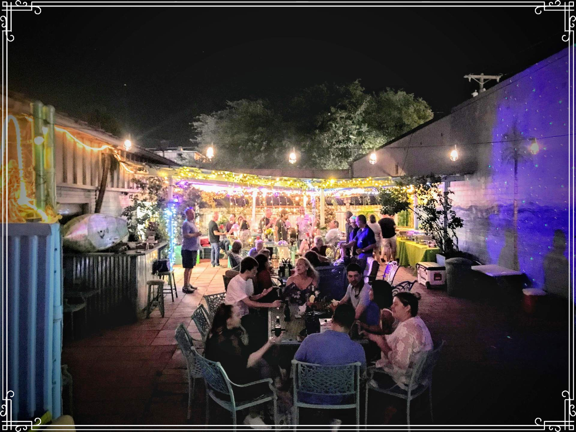 A group of people are sitting at tables outside at night.