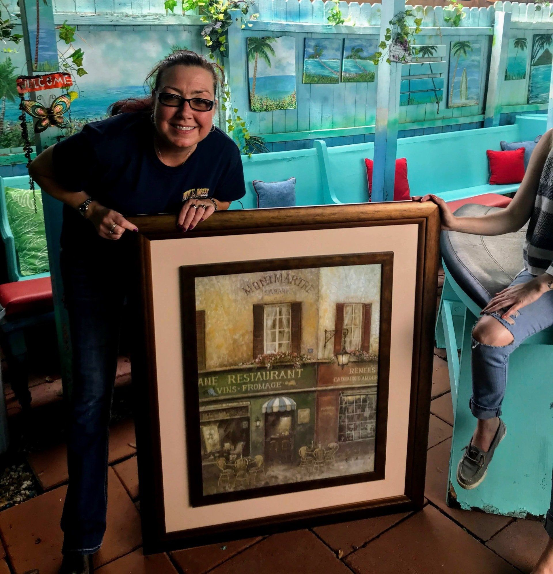 A woman is holding a framed picture of a restaurant