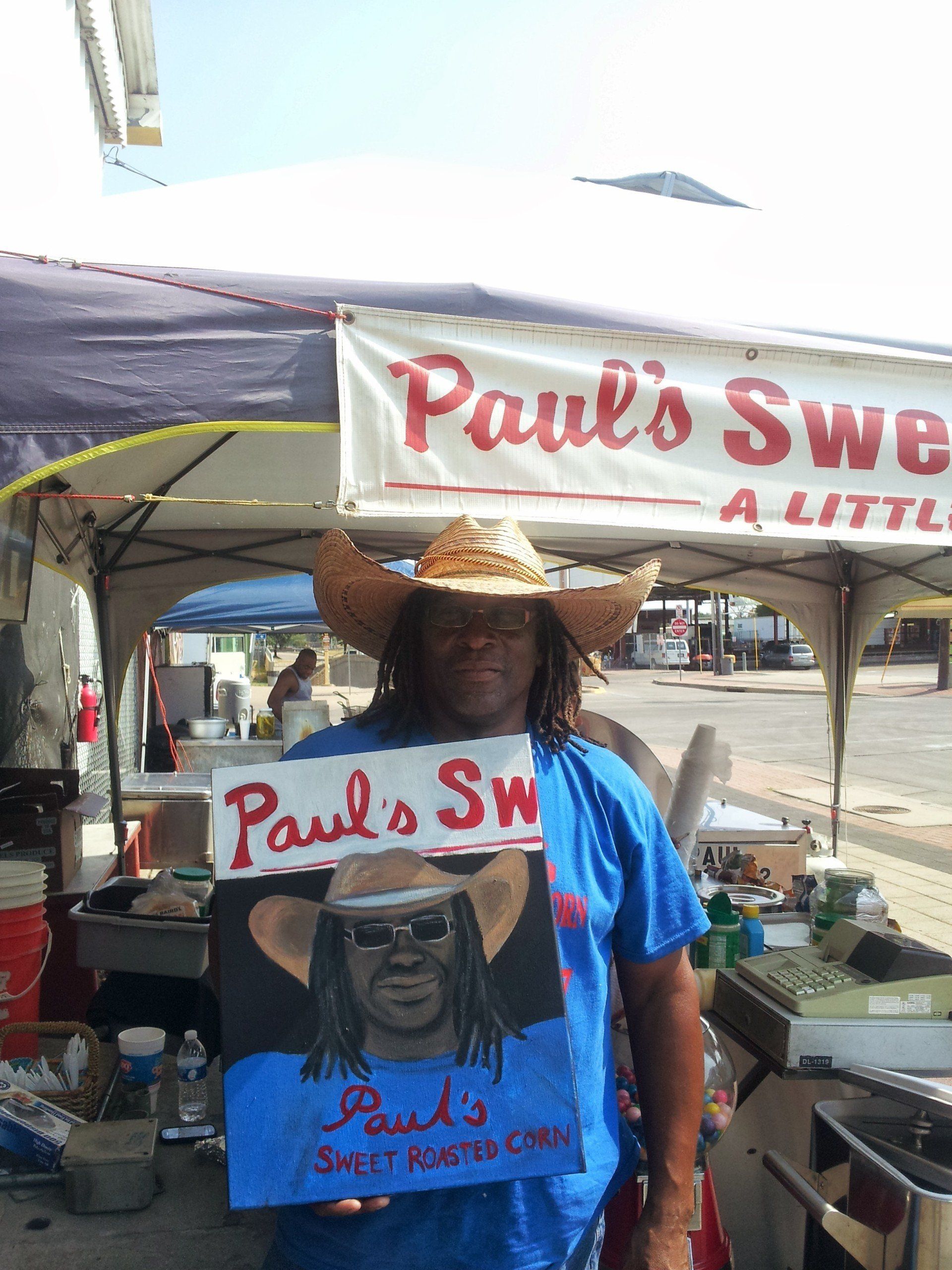 A man in a cowboy hat is holding a sign that says paul 's sw