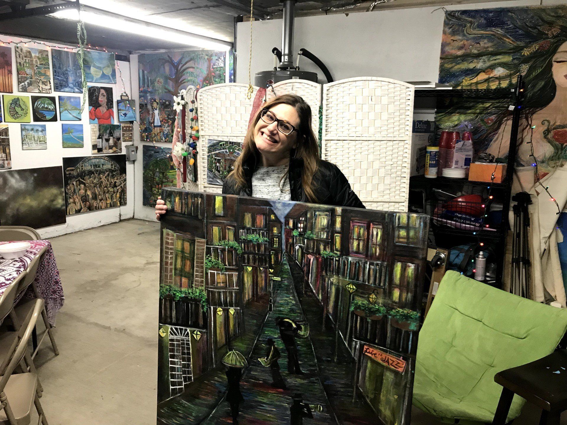 A woman is holding a large painting in a room.