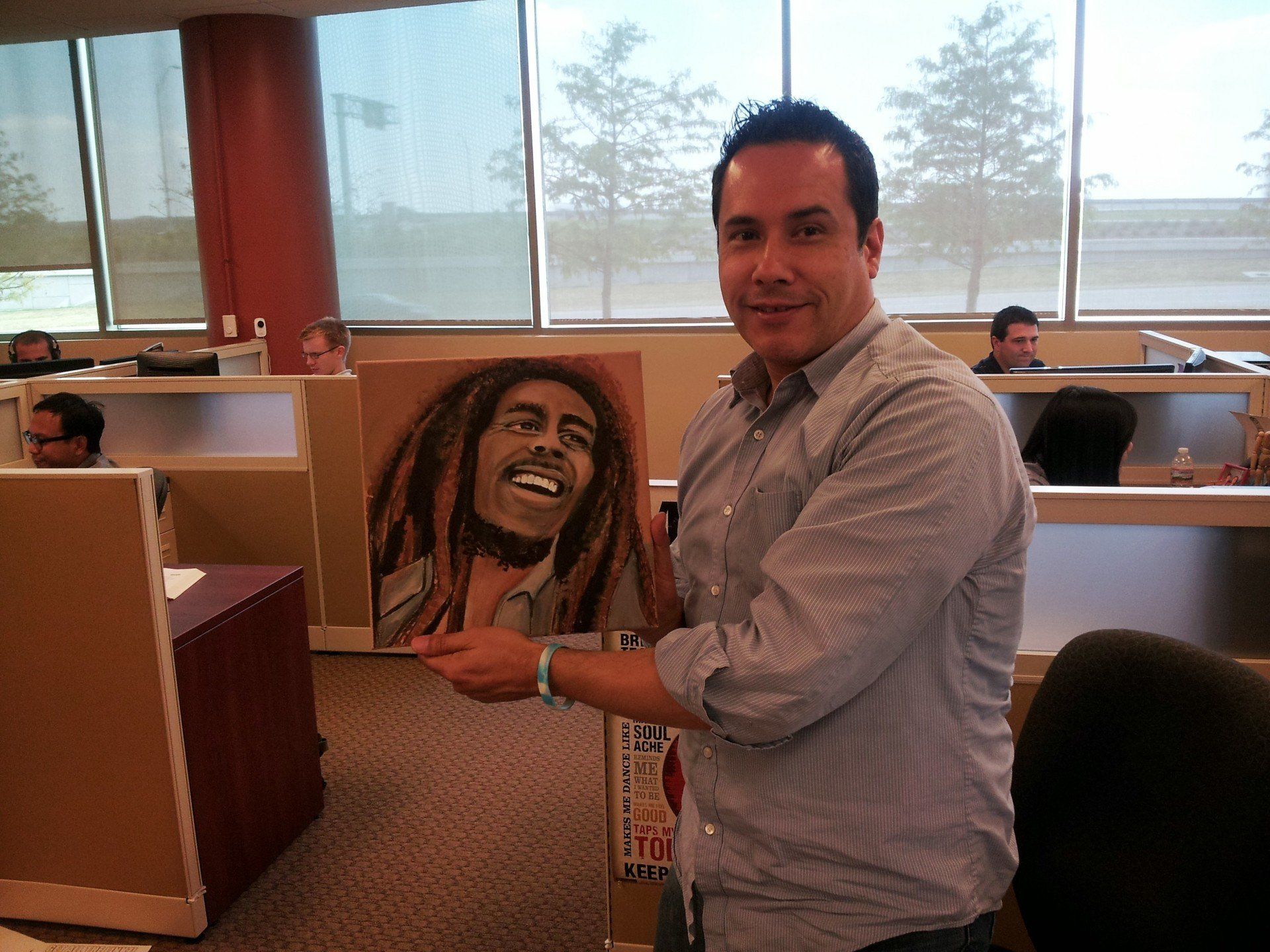 A man holding a painting of bob marley in an office