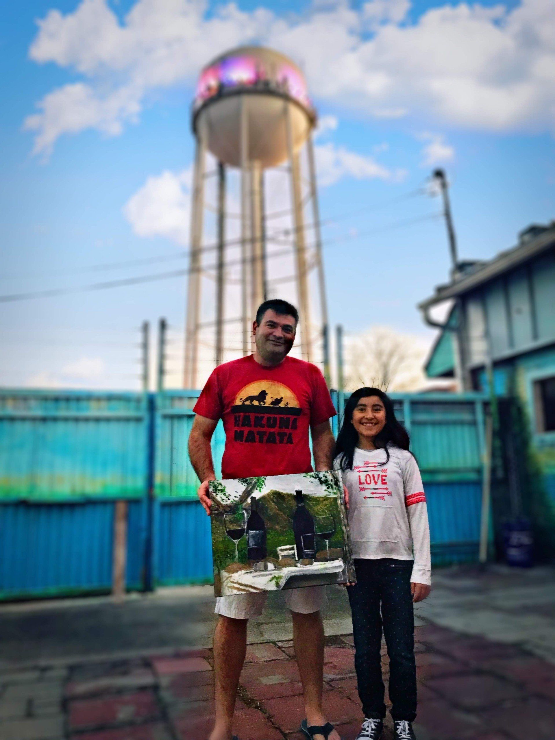 A man and a girl are standing in front of a water tower.