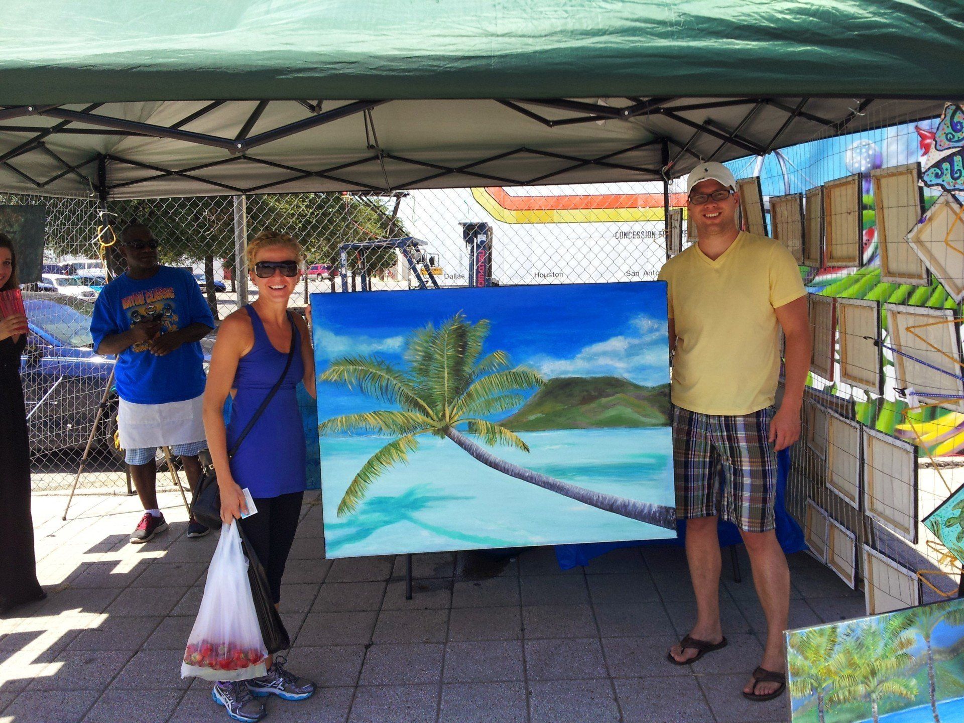 A man and a woman standing in front of a painting of a palm tree