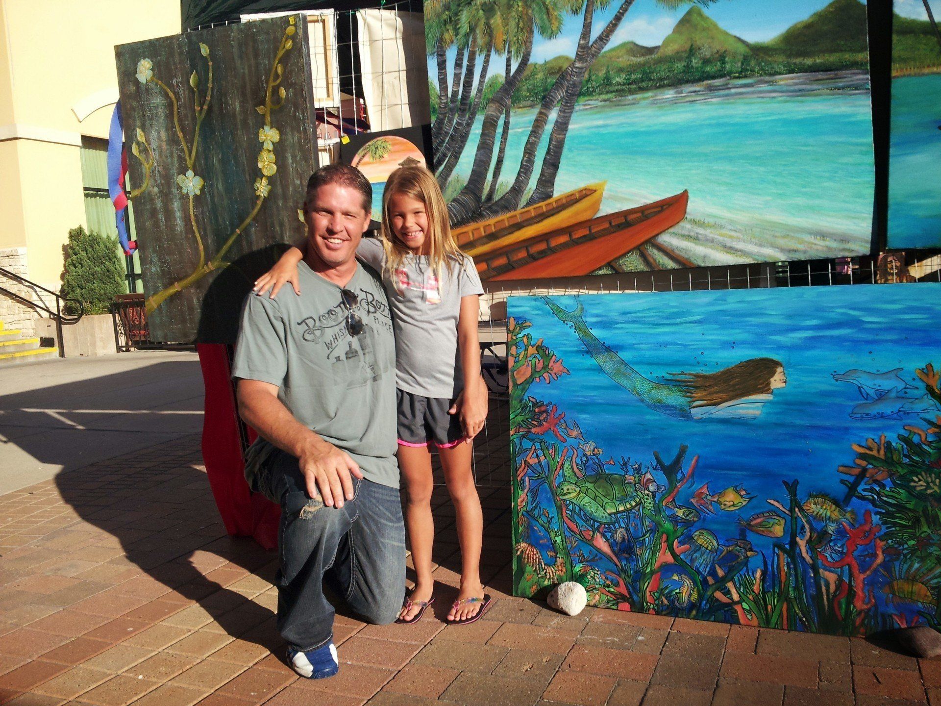A man and a little girl are posing in front of a painting