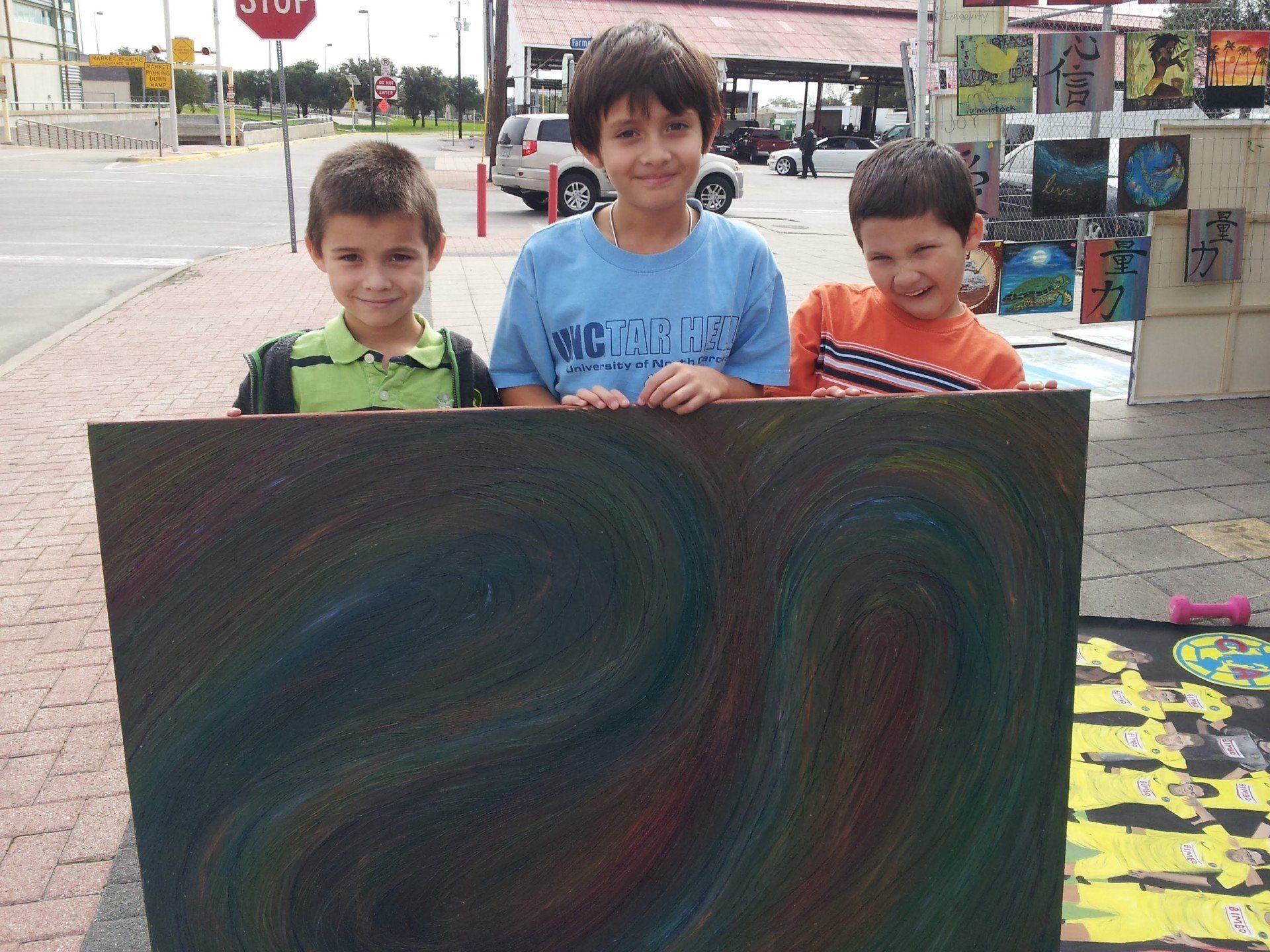 Three young boys holding a painting that says big