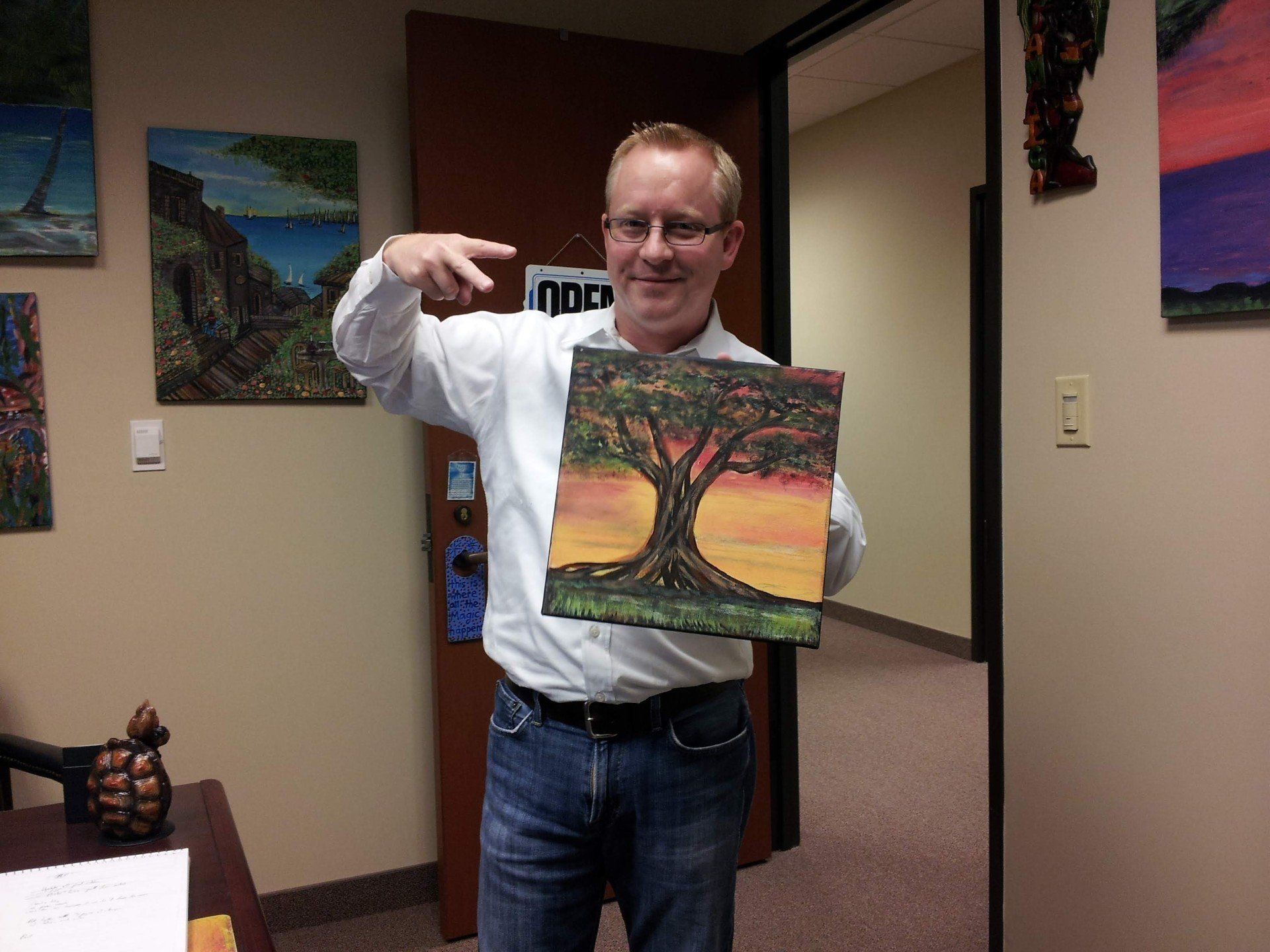 A man is pointing at a painting of a tree