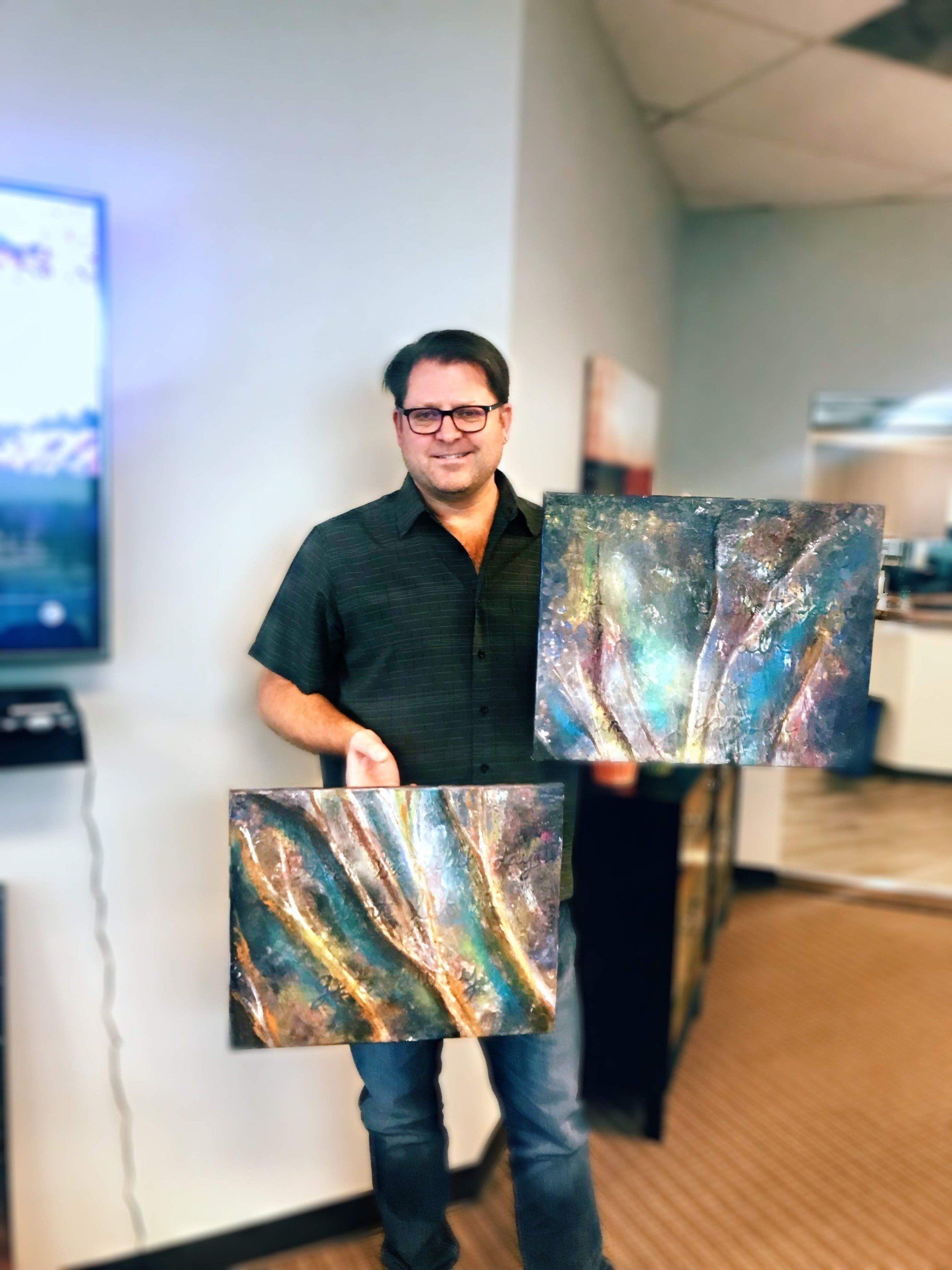 A man is holding two paintings in his hands