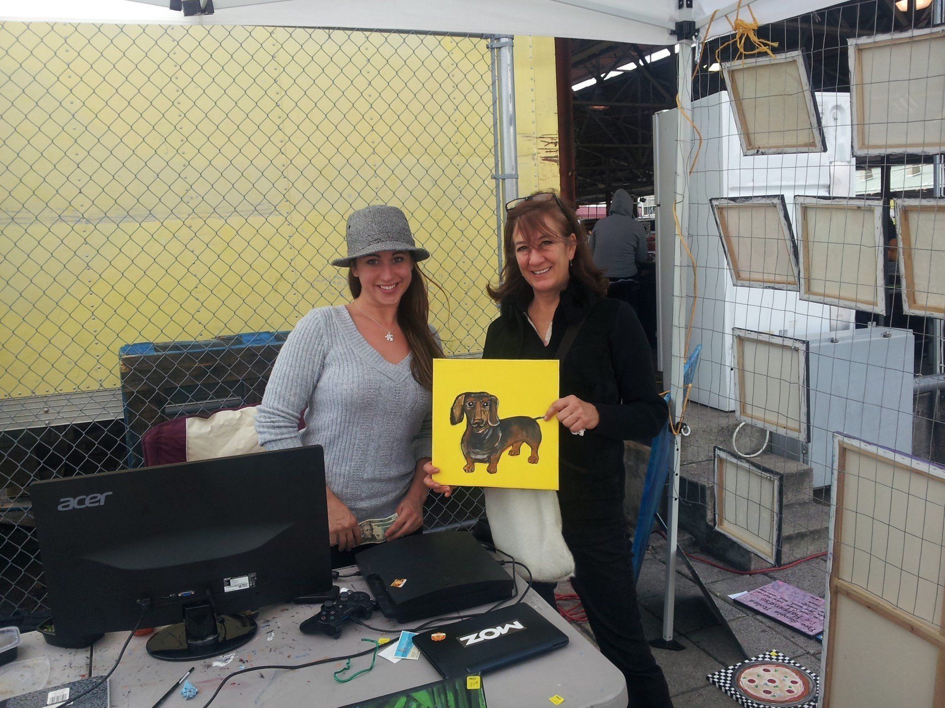 Two women standing next to each other holding a picture of a dachshund