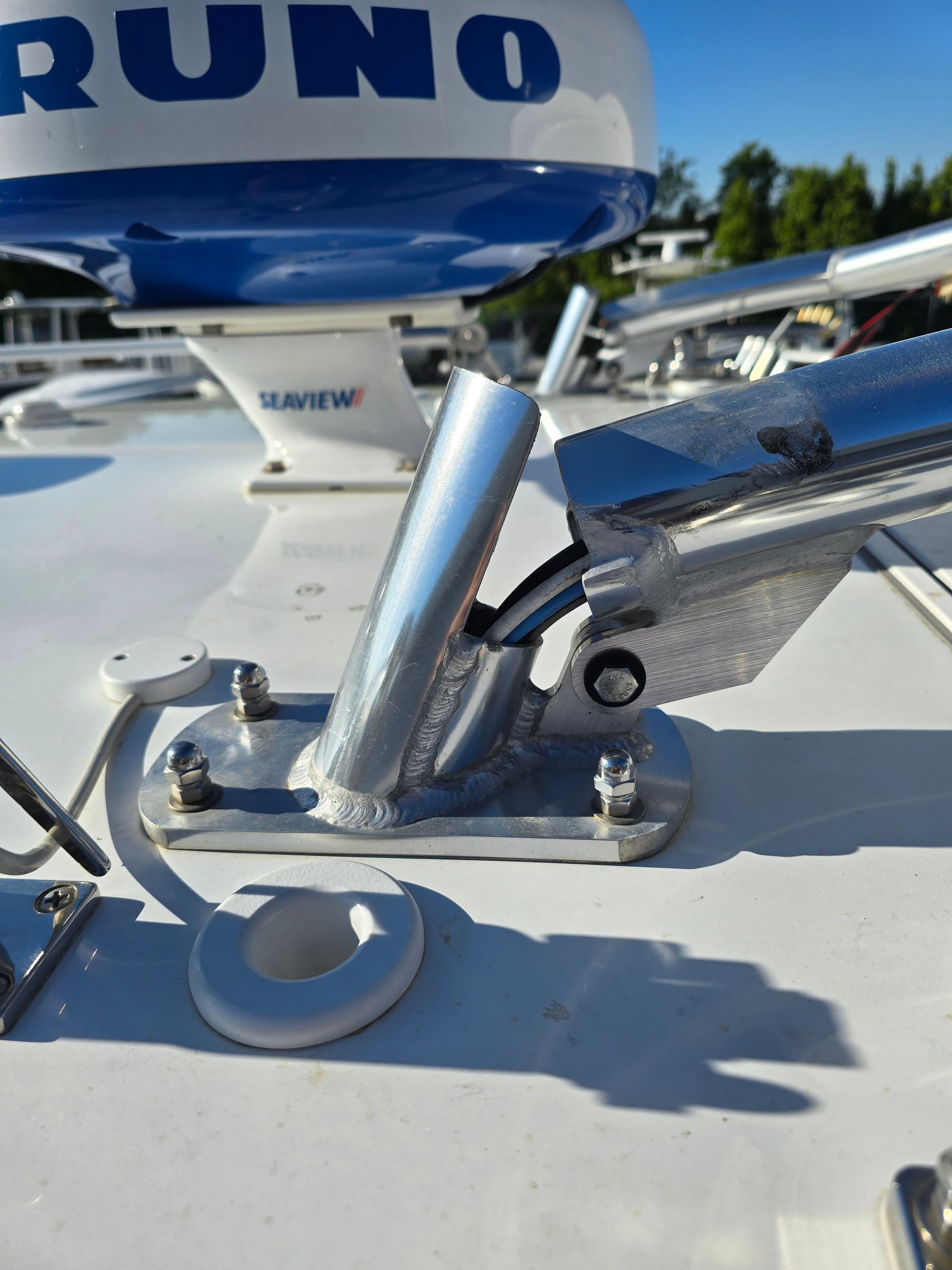 Silver fishing rod holder mounted on a white boat deck, with a radar dome in the background.