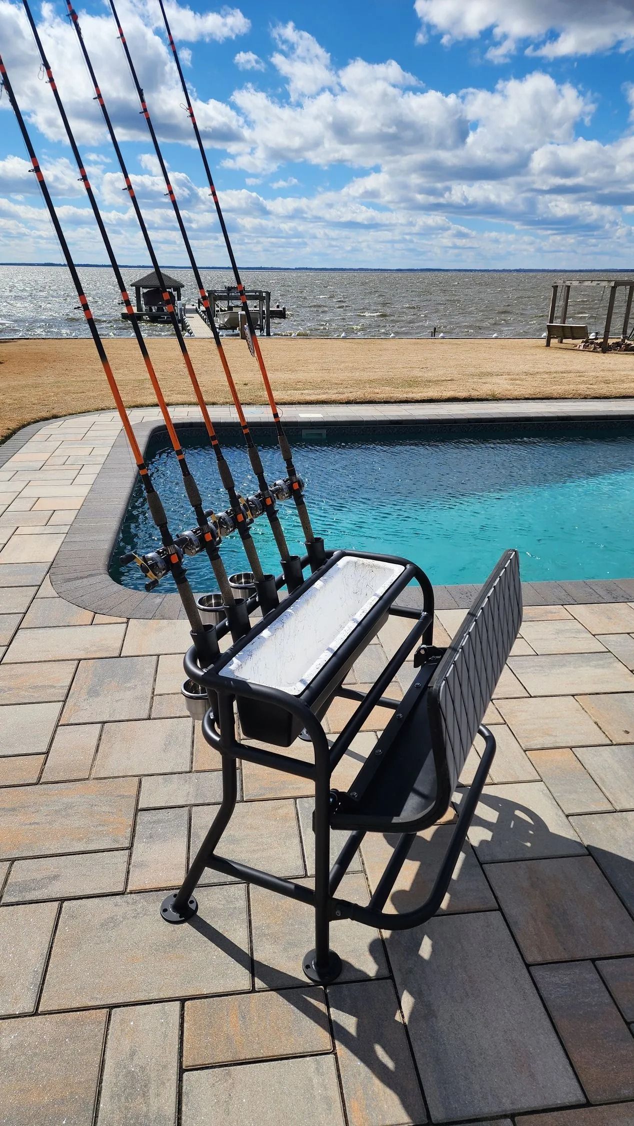 Fishing rod holder chair by a pool, with ocean background.