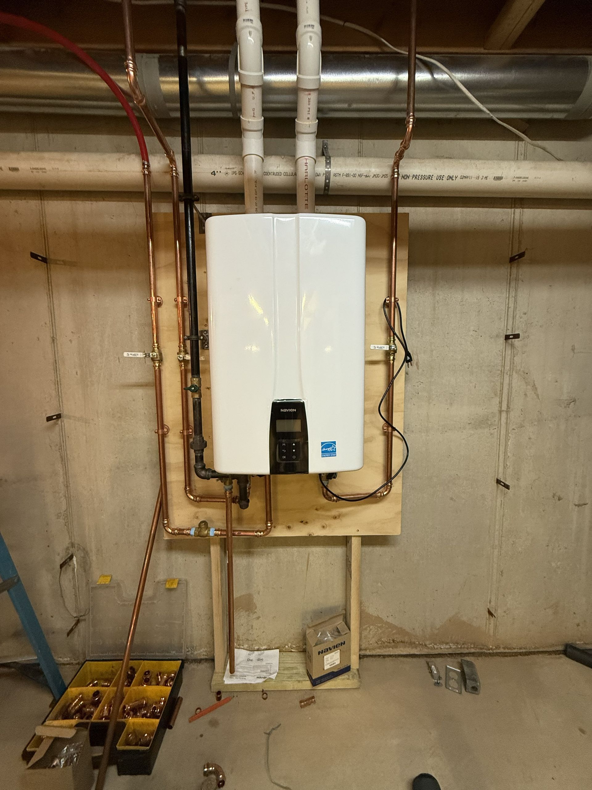 A person’s hands using a screwdriver to perform maintenance on a wall-mounted electric water heater.