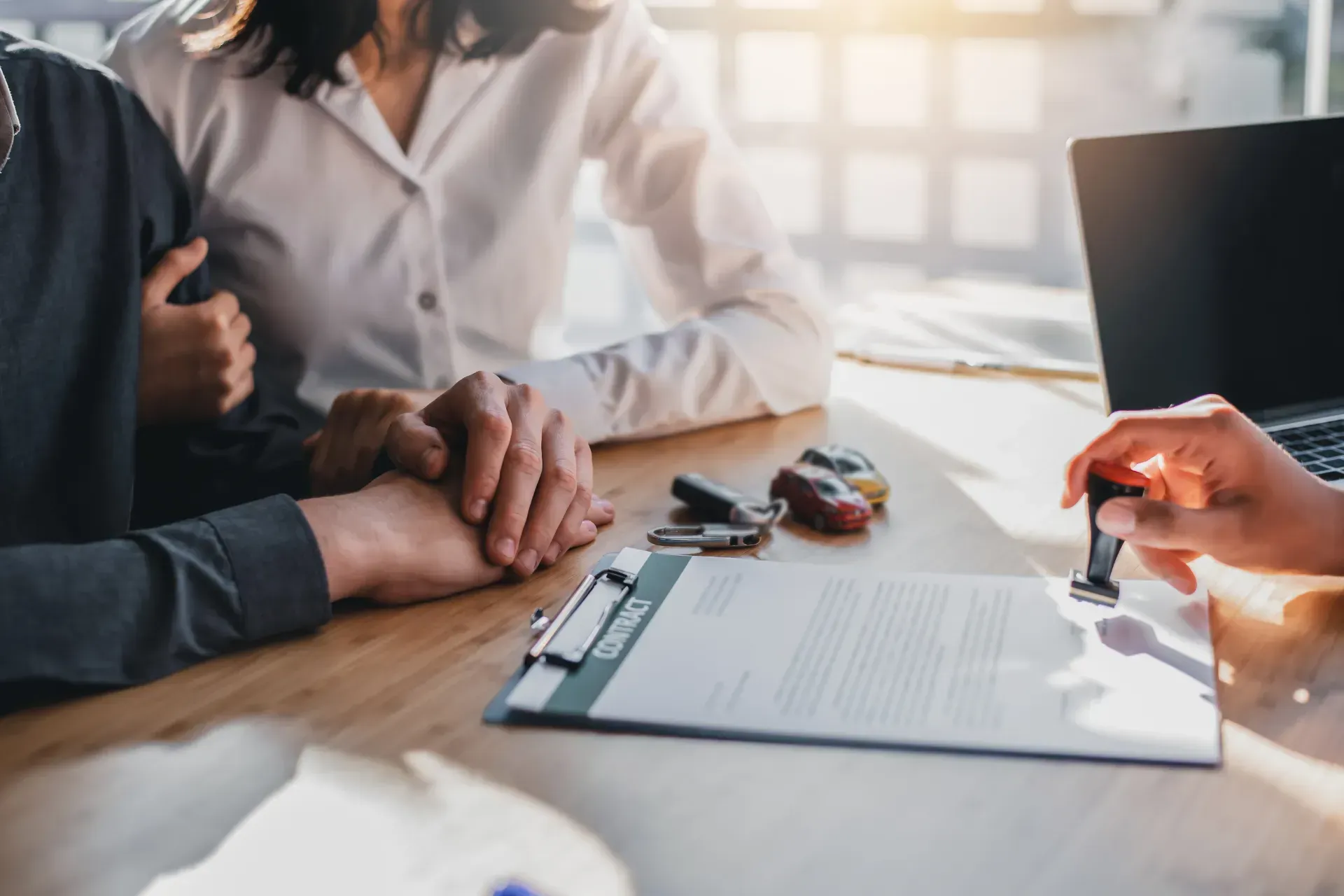 A Man And A Woman Are Sitting At A Table Signing A Car Lease Agreement — Brown & Co Finance in Dalby, QLD