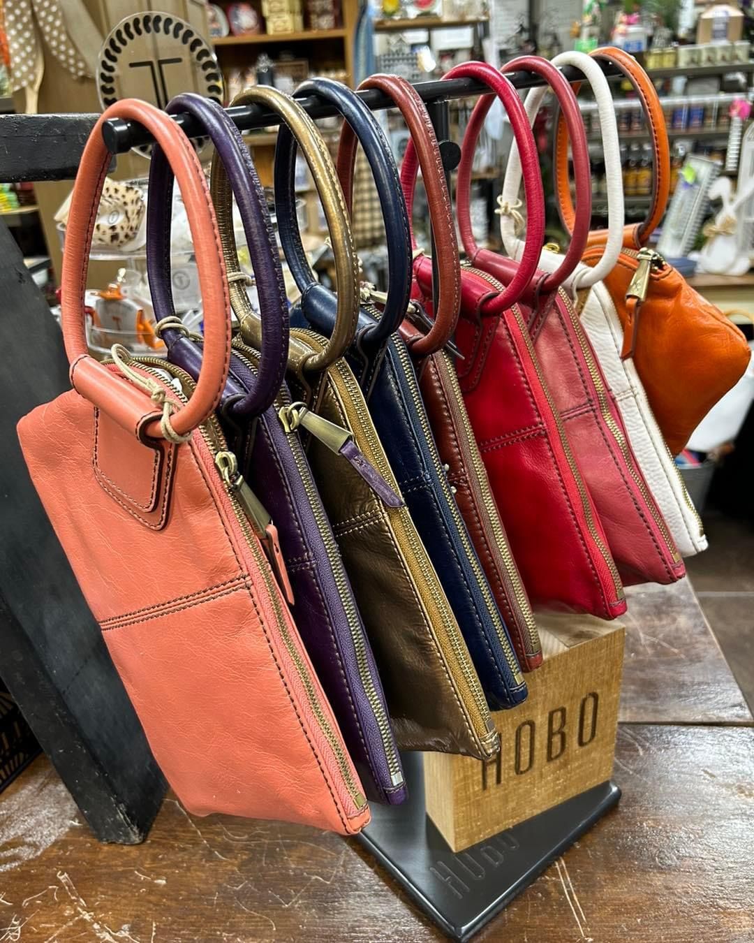 A bunch of handbags are hanging on a rack in a store.