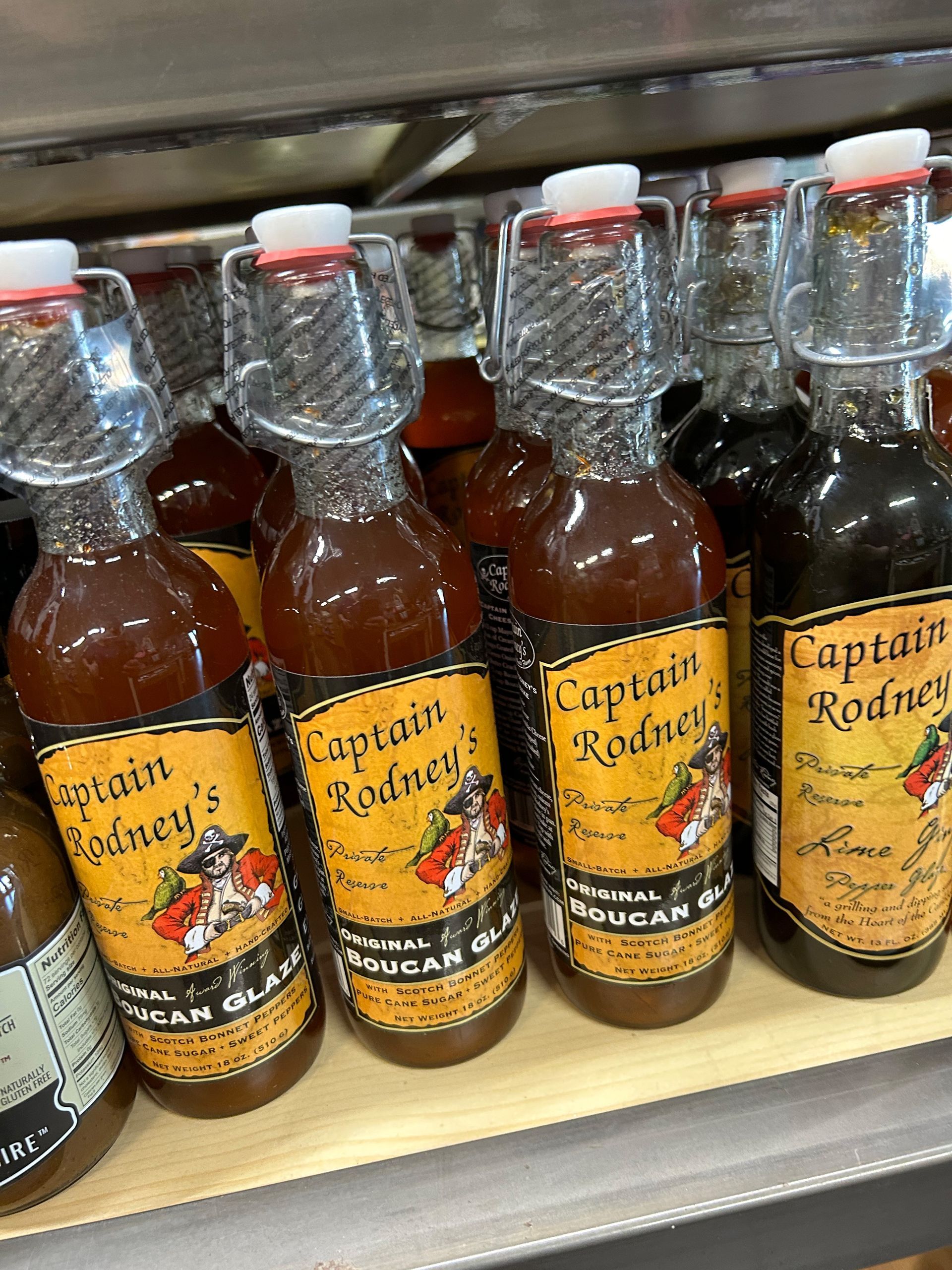 Several bottles of captain rodney 's cider are lined up on a shelf.