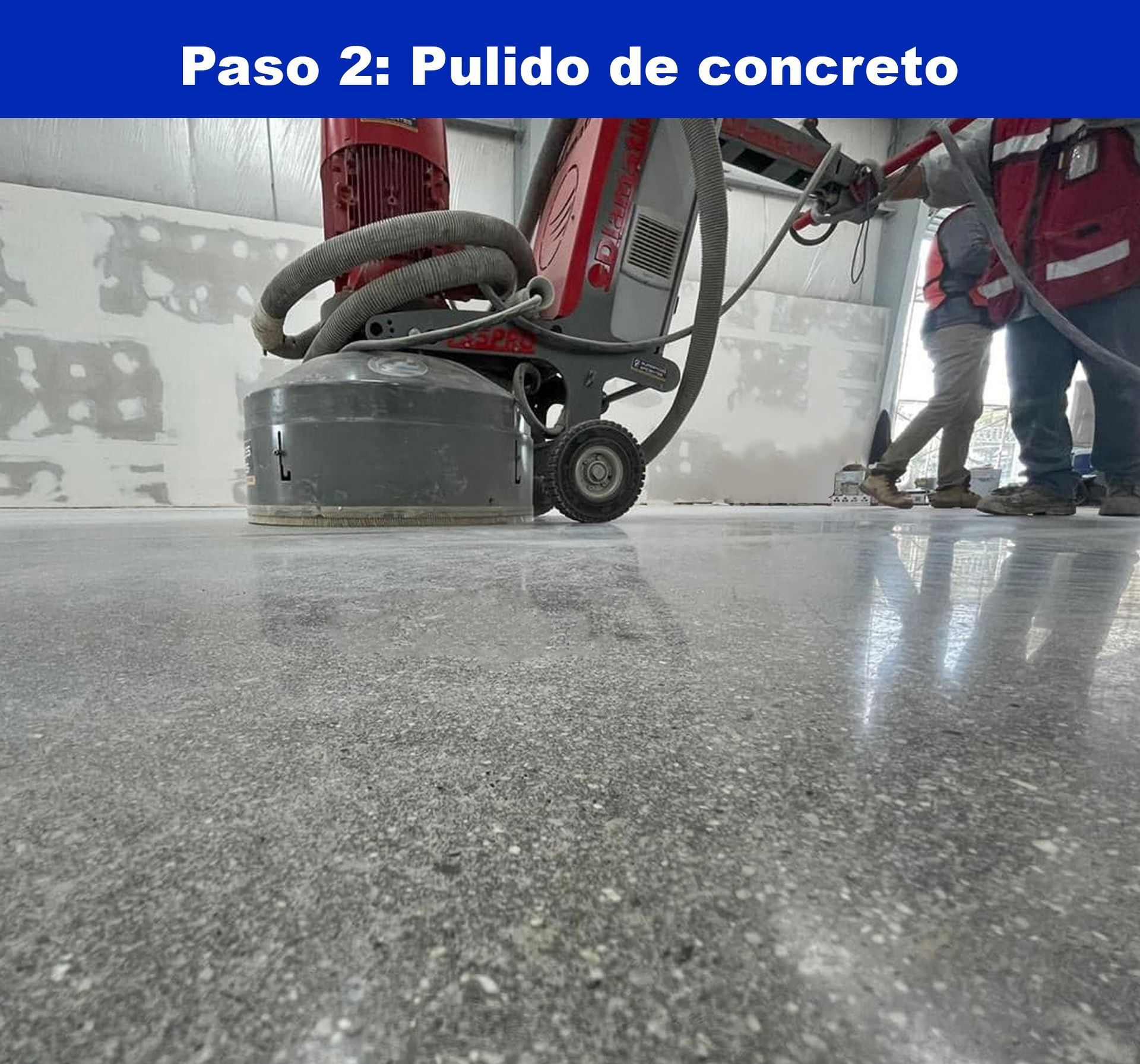 Un trabajador utiliza una máquina industrial roja para pulir un suelo de hormigón, creando una superficie lisa y reflectante.