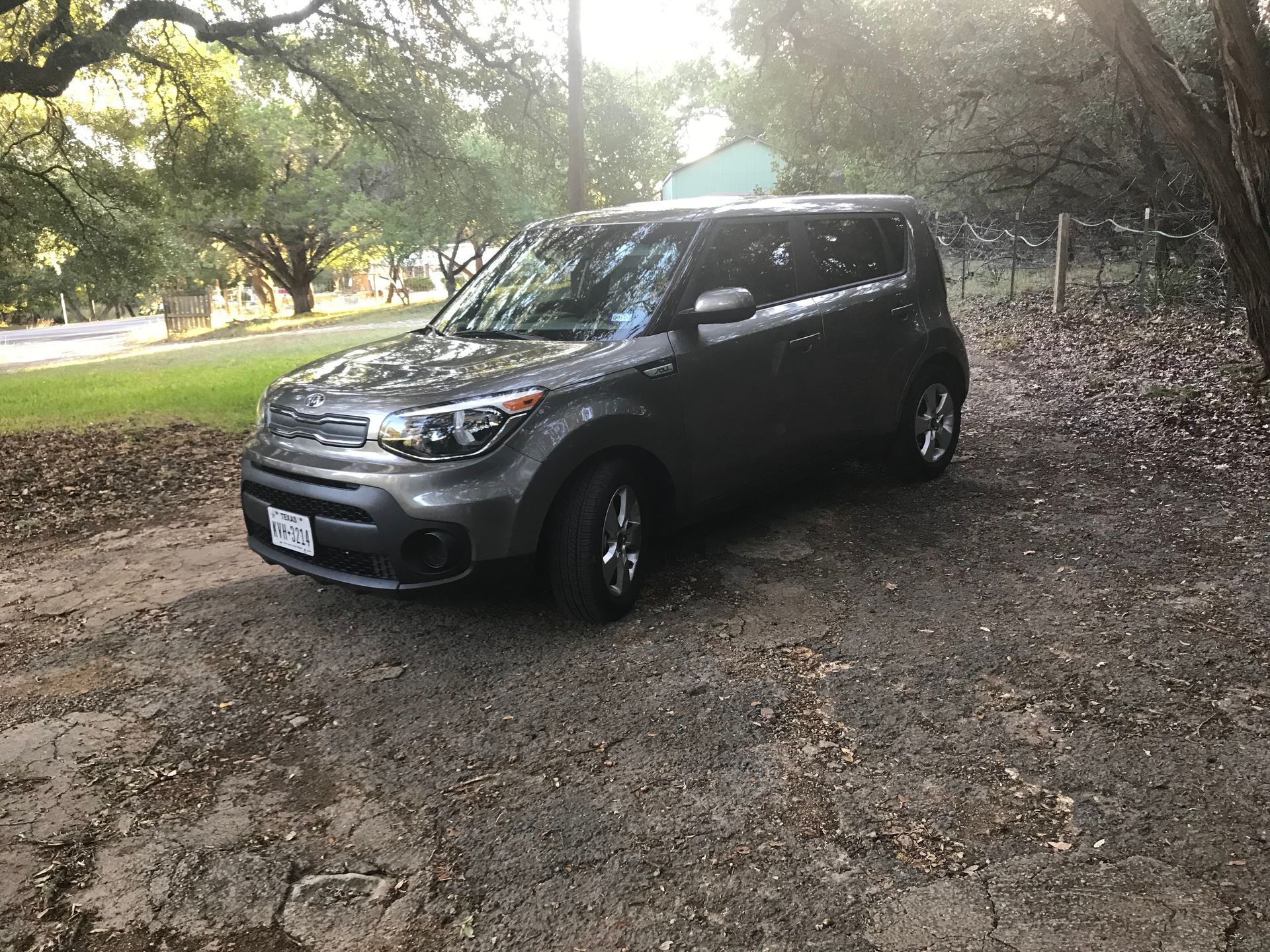 Car parked on a gravel driveway with trees in the background.
