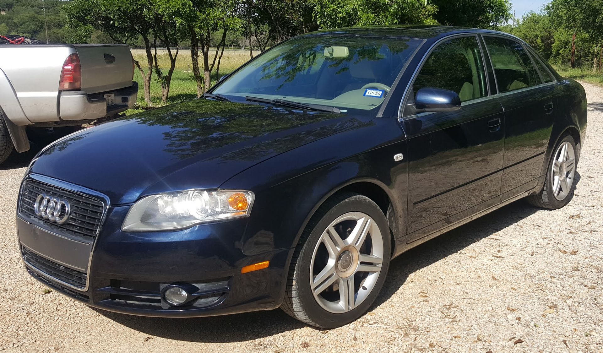 A black audi is parked in a gravel lot
