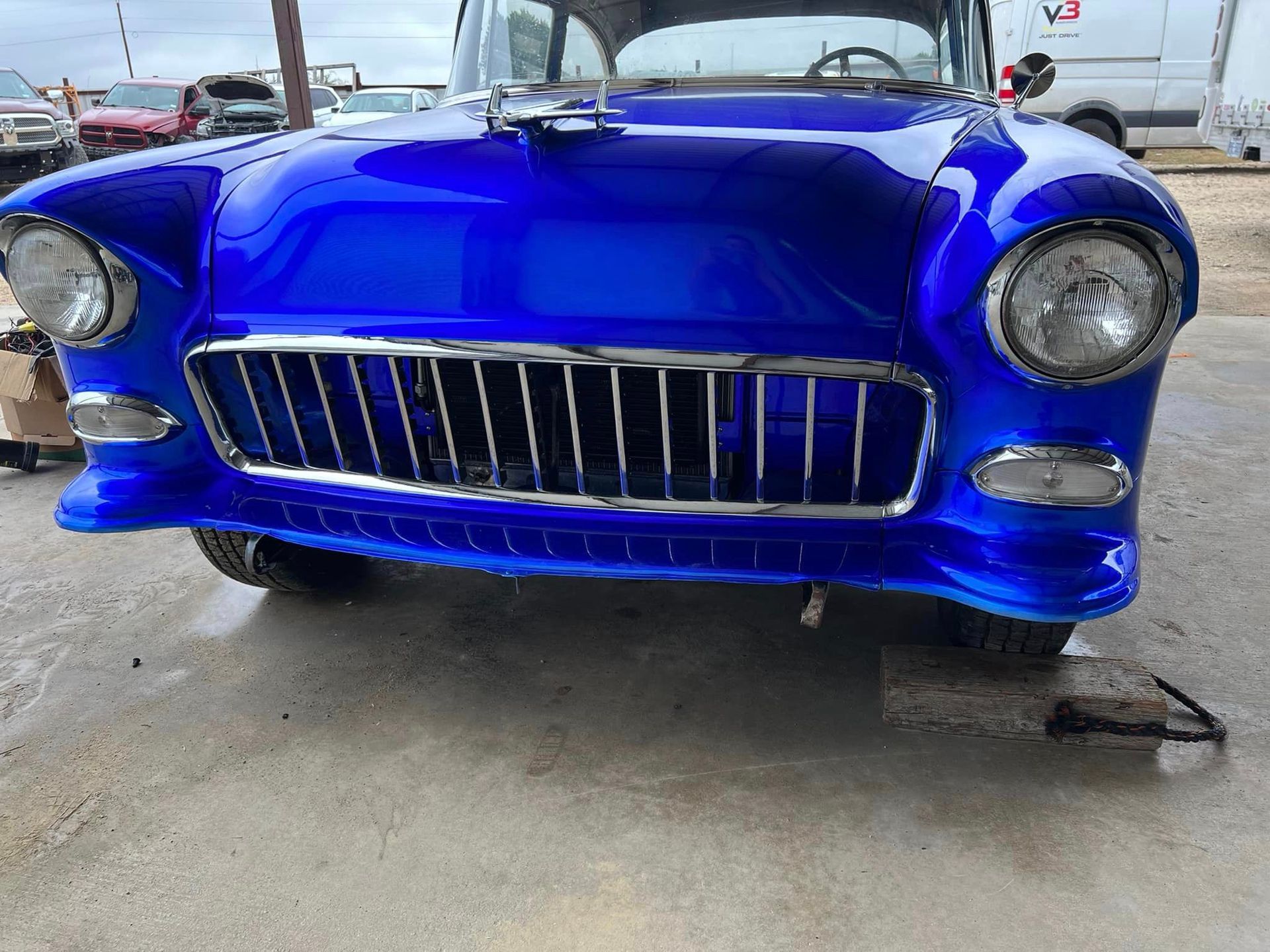 A blue car with a chrome grille is parked in a parking lot.