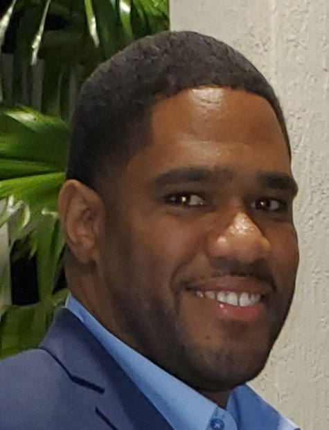 A man in a suit and blue shirt is smiling for the camera.