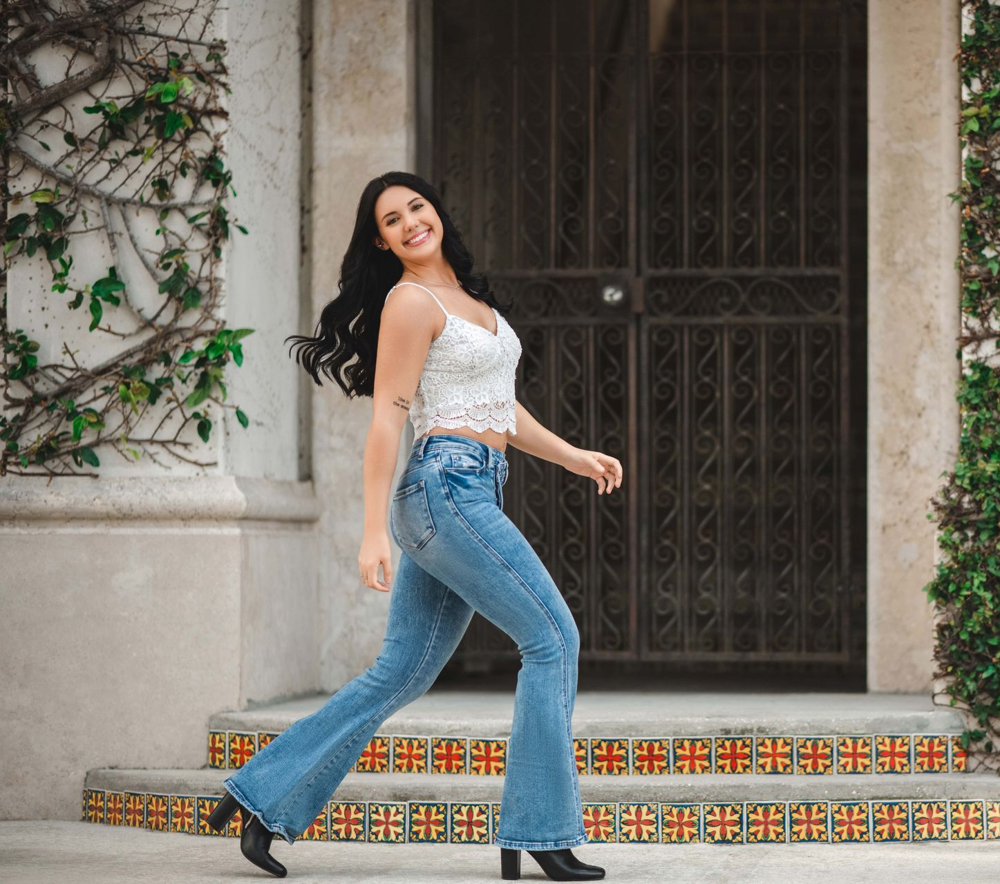 Woman in lace top and bell bottoms walking toward camera on steps.